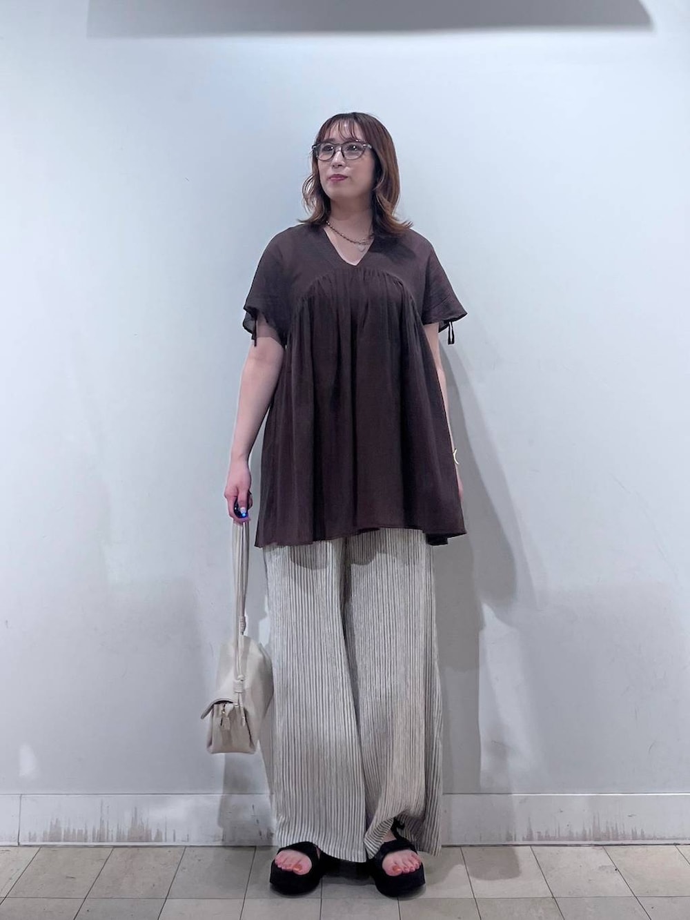 ベージュ系のショルダーバッグ、ベージュ系のその他パンツ、ブラウン系のシャツ/ブラウスを着用したレディースの夏コーディネートの6枚目の写真