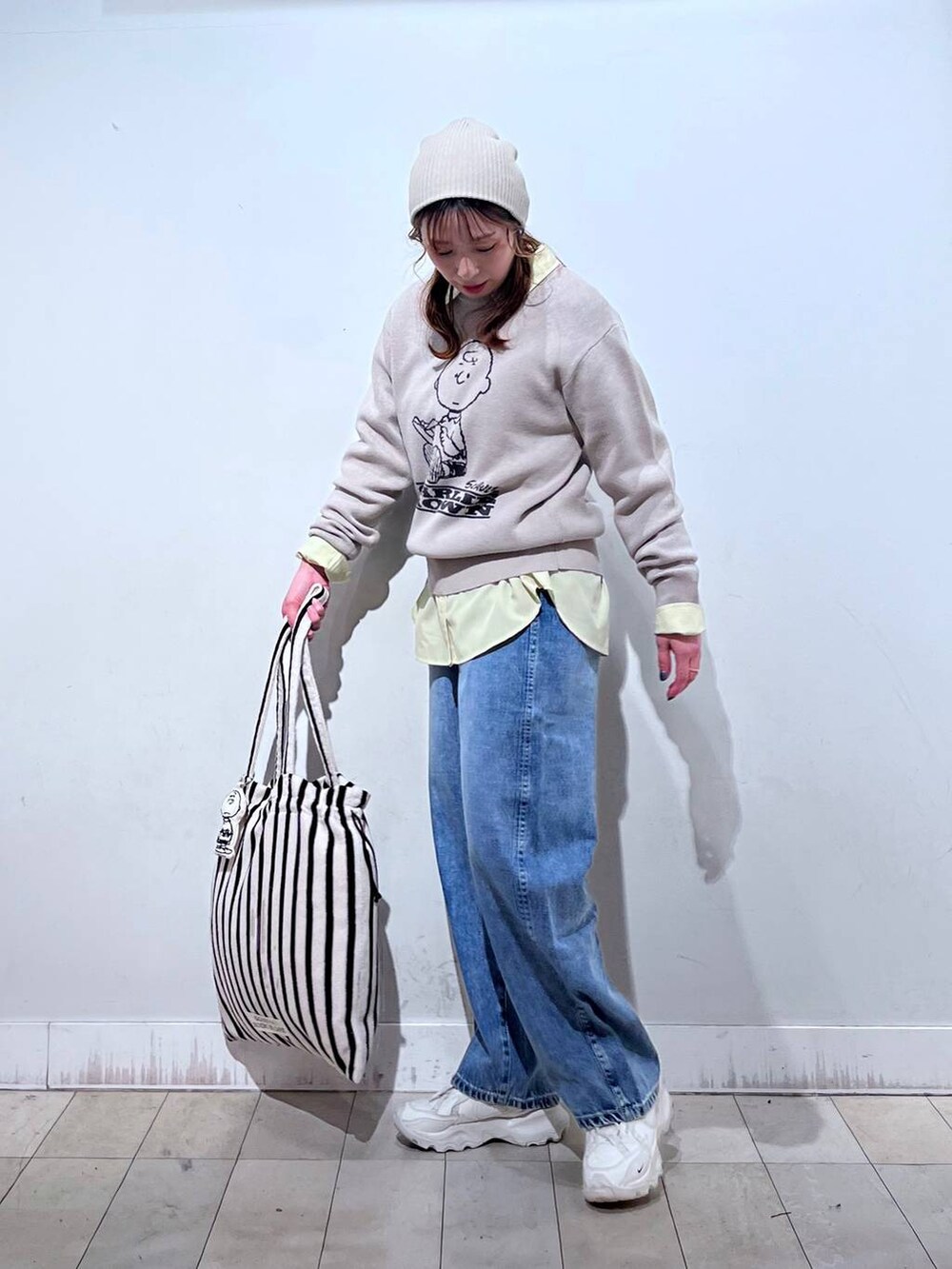 イエロー系のシャツ/ブラウス、ブルー系のデニムパンツ、ベージュ系のニット/セーターを着用したレディースの冬コーディネートの3枚目の写真