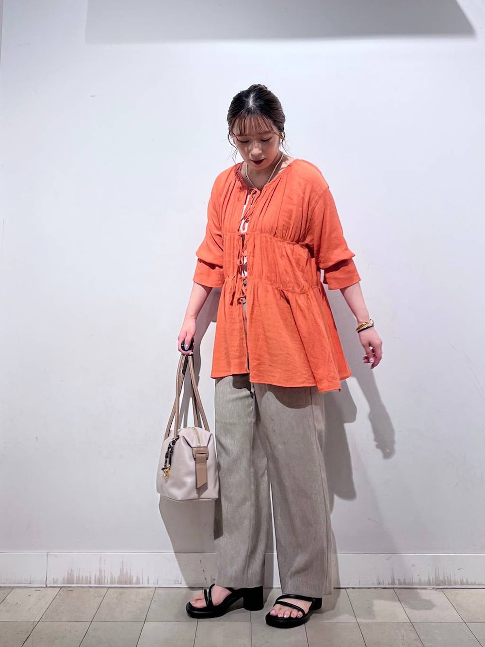 オレンジ系のシャツ/ブラウス、ホワイト系のタンクトップ、ベージュ系のボストンバッグを着用したレディースの秋コーディネートの5枚目の写真