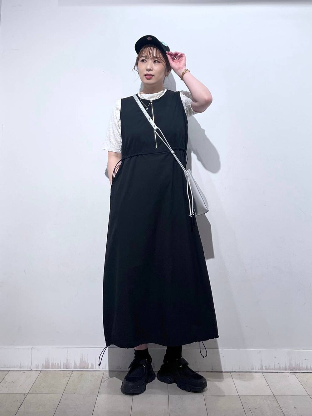 ブラック系のスニーカー、シルバー系のショルダーバッグ、ベージュ系のTシャツ/カットソーを着用したレディースの夏コーディネートの5枚目の写真