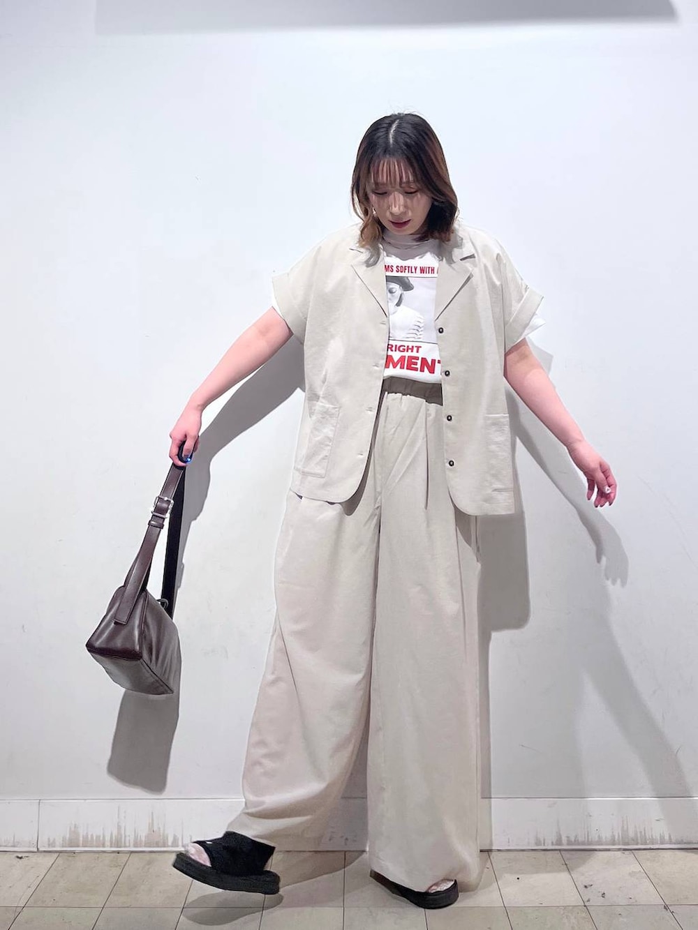 ブラウン系のショルダーバッグ、ベージュ系のその他パンツ、ホワイト系のTシャツ/カットソーを着用したレディースの夏コーディネートの6枚目の写真