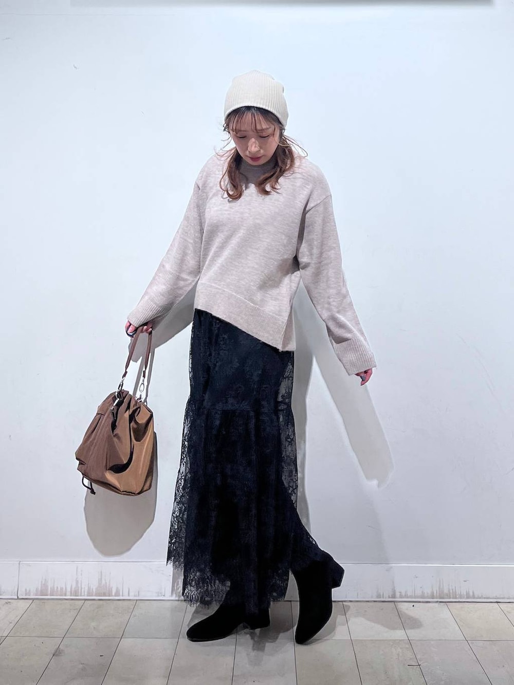 ブラウン系のショルダーバッグ、ベージュ系のダウンジャケット/コート、イエロー系のワンピースを着用したレディースの冬コーディネートの4枚目の写真