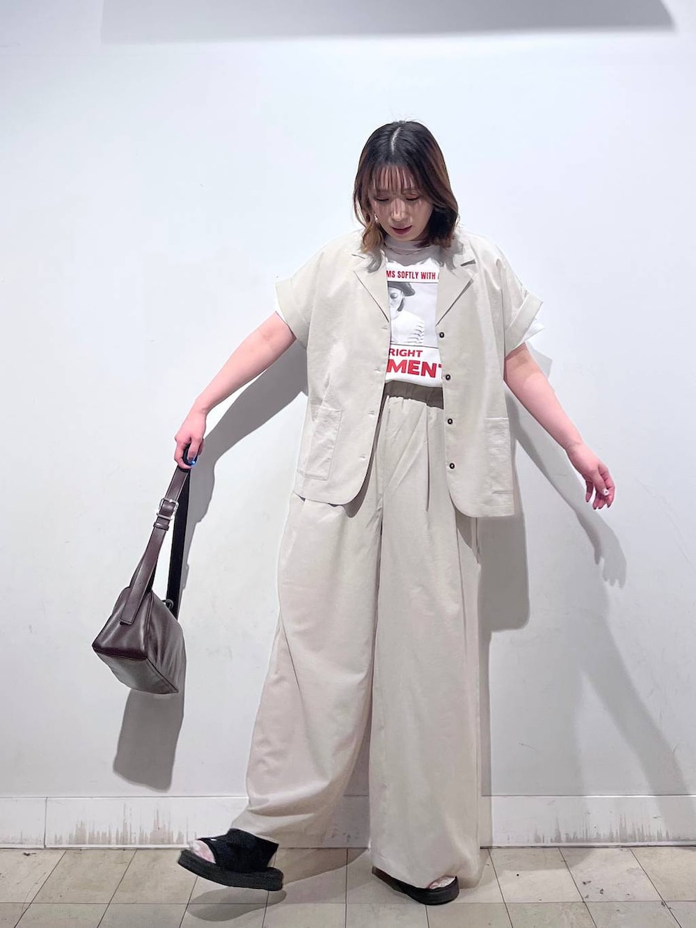 ブラウン系のショルダーバッグ、ホワイト系のTシャツ/カットソー、ブラック系のサンダルを着用したレディースの春コーディネートの4枚目の写真