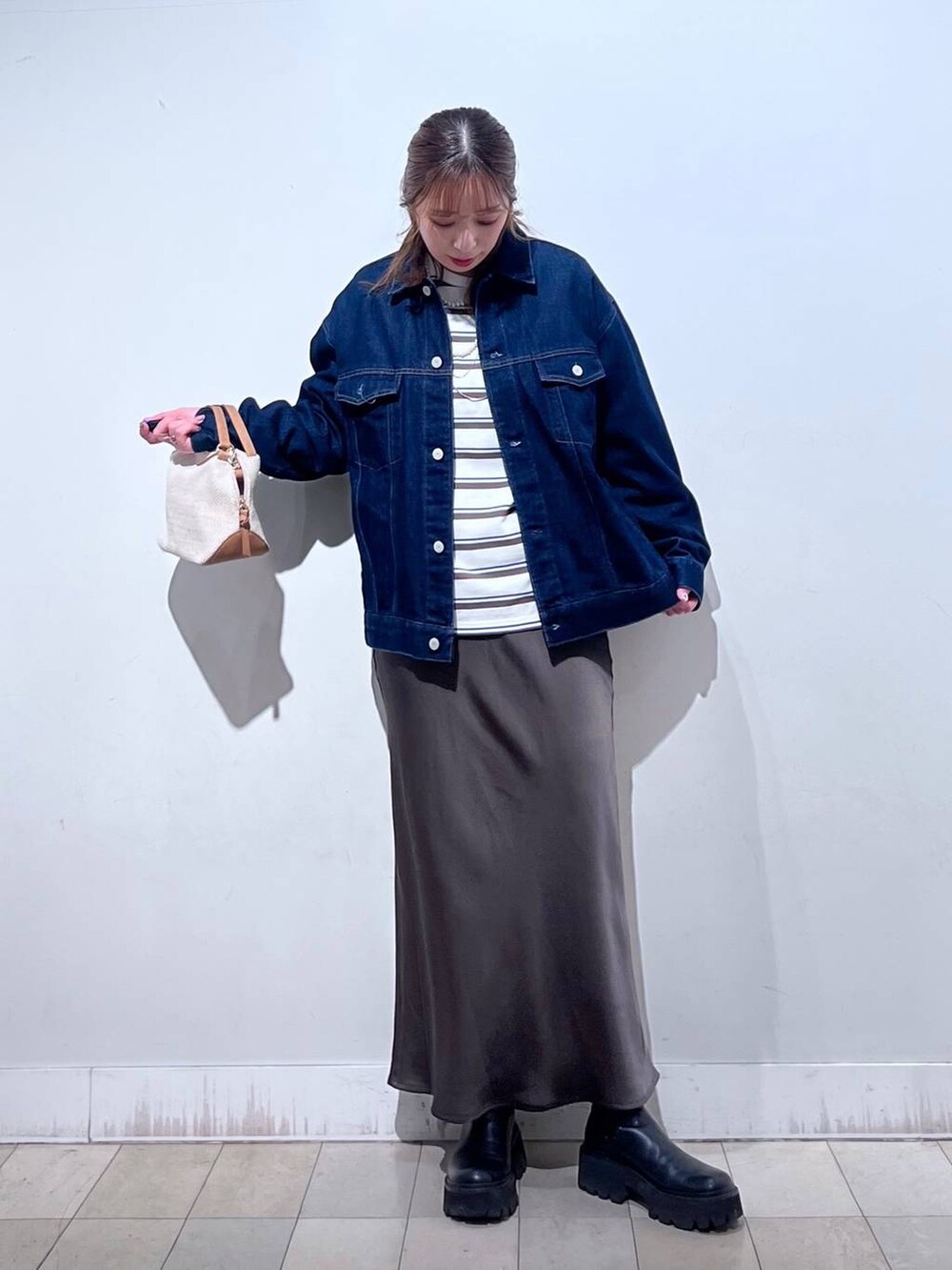 ホワイト系のショルダーバッグ、ブルー系のデニムジャケット、ブラウン系のスカートを着用したレディースの冬コーディネートの3枚目の写真