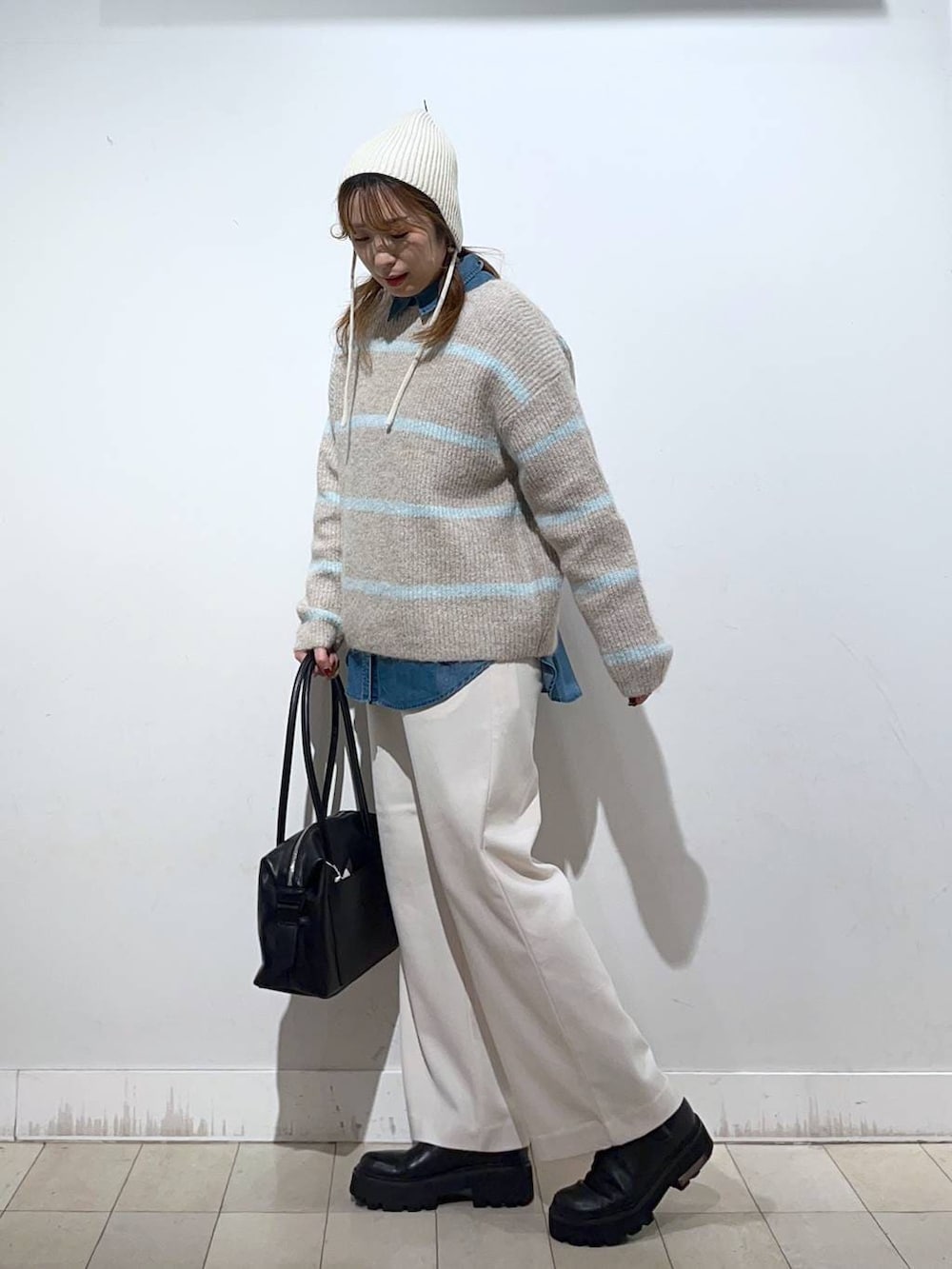 ブラック系のボストンバッグ、ブルー系のシャツ/ブラウス、ベージュ系のニット/セーターを着用したレディースの冬コーディネートの2枚目の写真