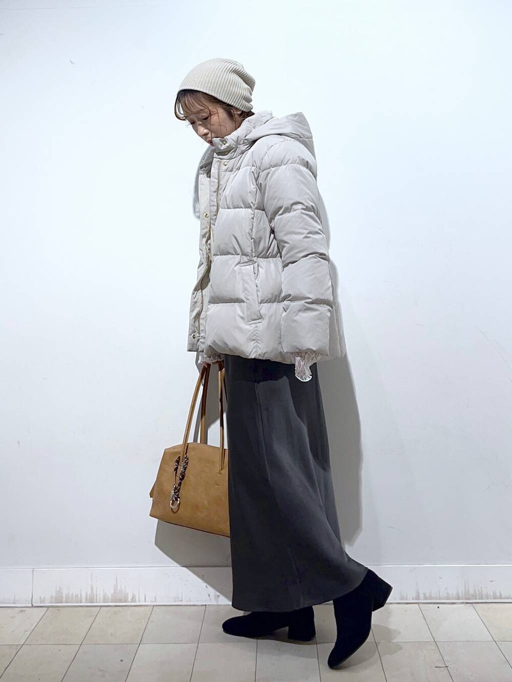 ブラウン系のボストンバッグ、ベージュ系のダウンジャケット/コート、ホワイト系のTシャツ/カットソーを着用したレディースの冬コーディネートの4枚目の写真