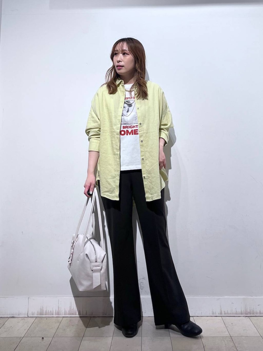 ホワイト系のボストンバッグ、ブラック系のブーツ、イエロー系のシャツ/ブラウスを着用したレディースの春コーディネートの5枚目の写真