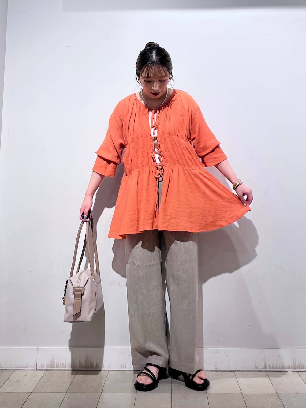 オレンジ系のシャツ/ブラウス、ホワイト系のタンクトップ、ベージュ系のボストンバッグを着用したレディースの秋コーディネートの6枚目の写真