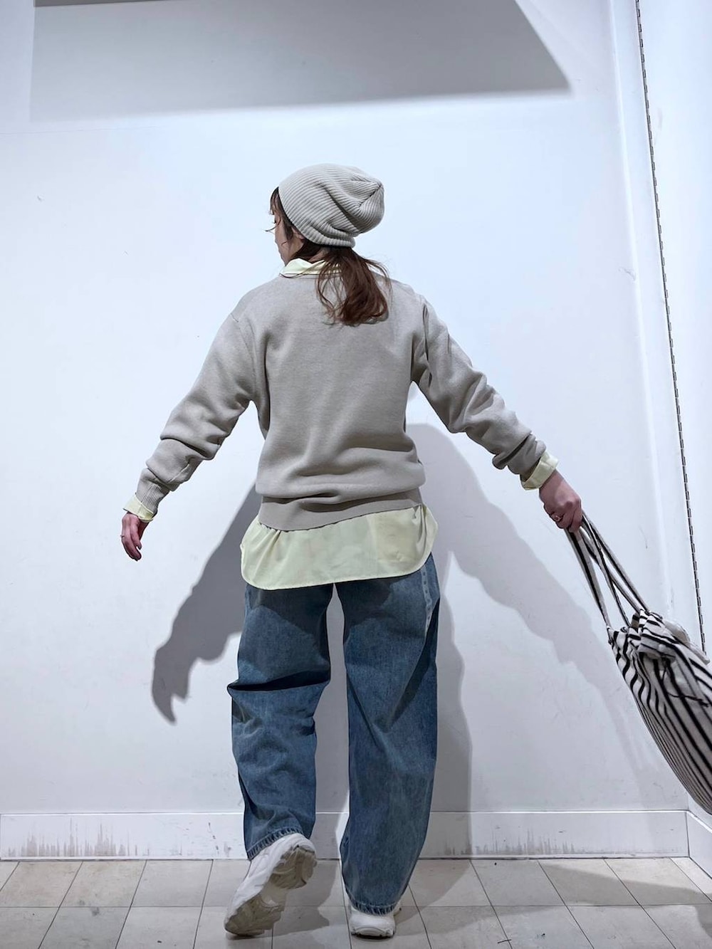 イエロー系のシャツ/ブラウス、ブルー系のデニムパンツ、ベージュ系のニット/セーターを着用したレディースの冬コーディネートの6枚目の写真