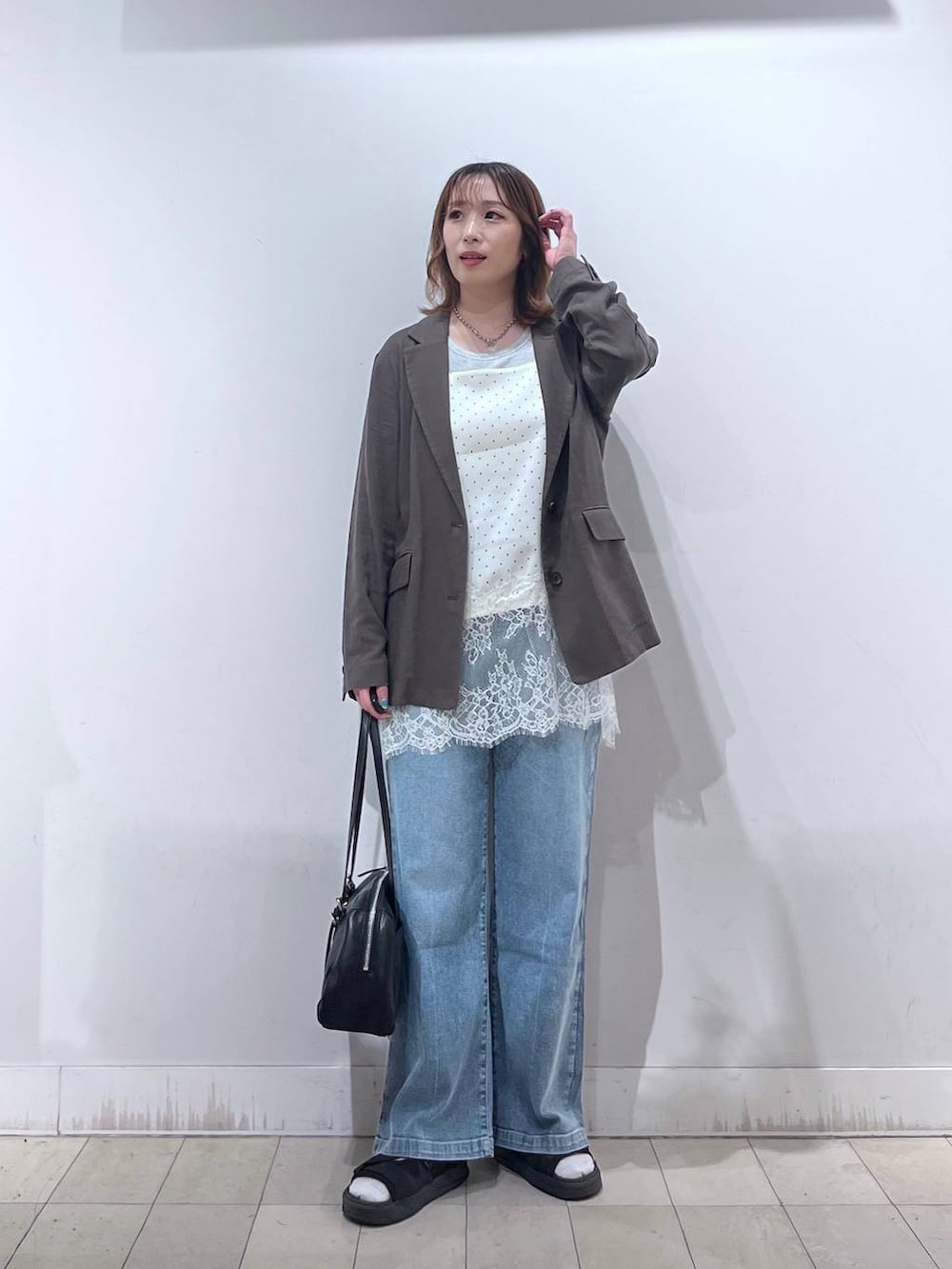 ブルー系のデニムパンツ、ブラウン系のテーラードジャケット、ホワイト系のキャミソールを着用したレディースの夏コーディネートの4枚目の写真