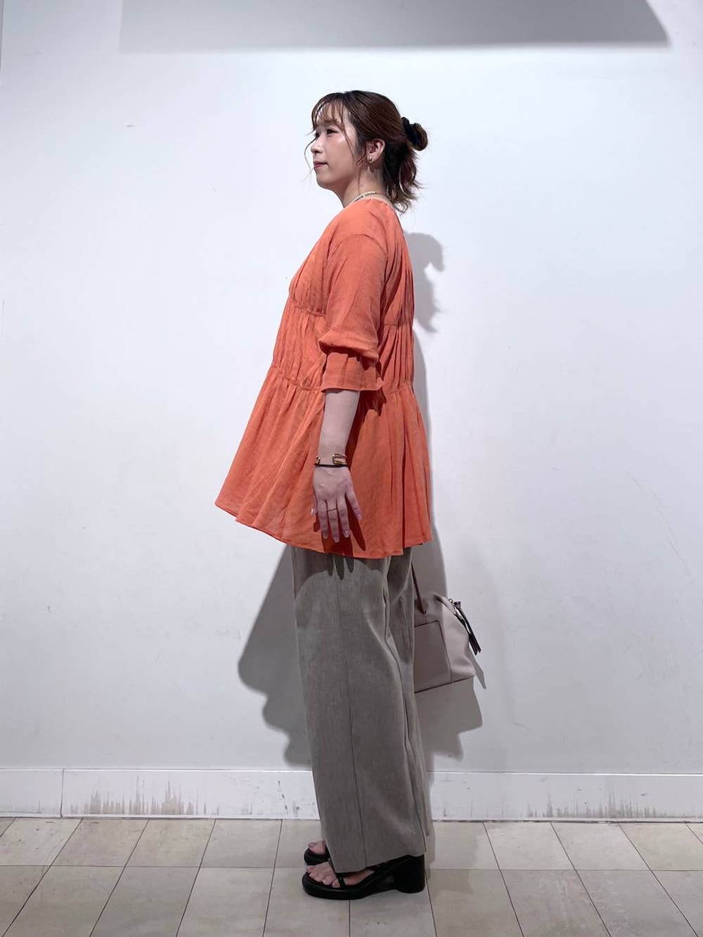 オレンジ系のシャツ/ブラウス、ホワイト系のタンクトップ、ベージュ系のボストンバッグを着用したレディースの秋コーディネートの3枚目の写真