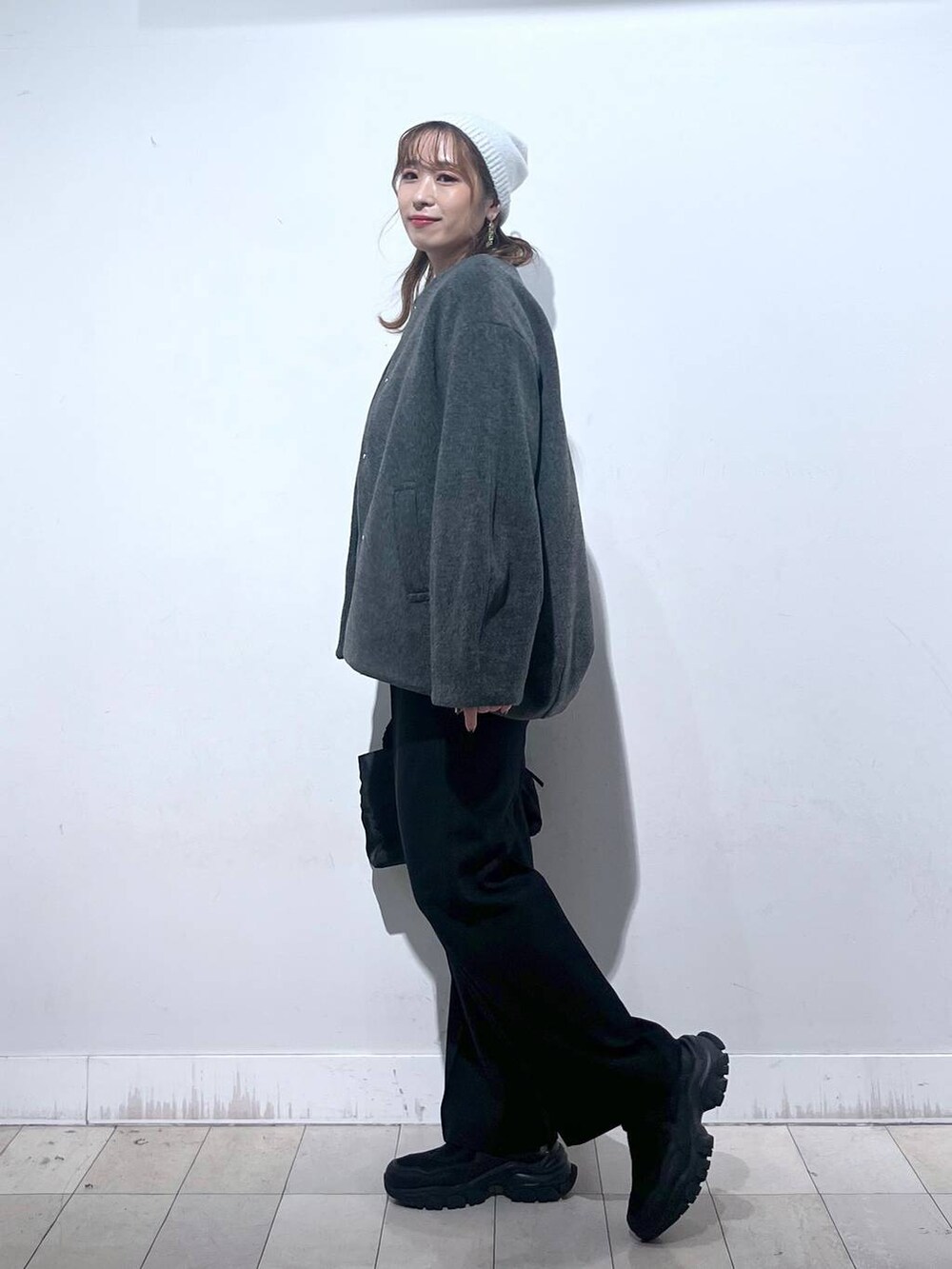 ブラック系のスニーカー、ブラック系のショルダーバッグ、グレー系のノーカラーコートを着用したレディースの秋コーディネートの2枚目の写真