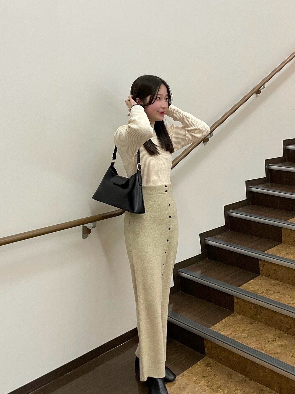 ホワイト系のニット/セーター、ホワイト系のスカート、ブラック系のブーツを着用したレディースの冬コーディネートの2枚目の写真