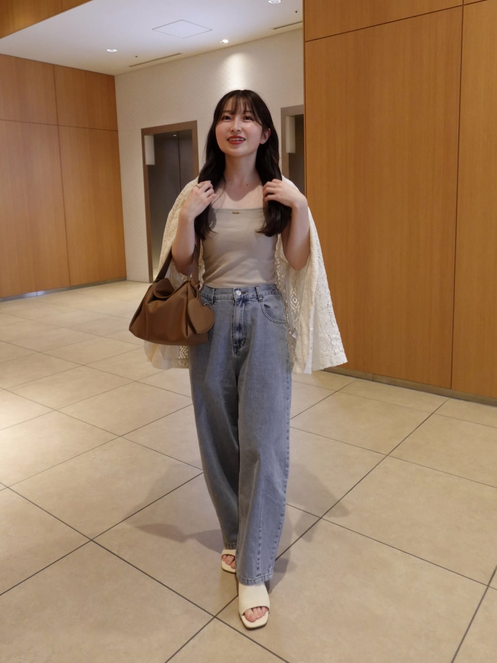 ベージュ系のキャミソール、ブルー系のデニムパンツ、ベージュ系のテーラードジャケットを着用したレディースの春コーディネートの5枚目の写真