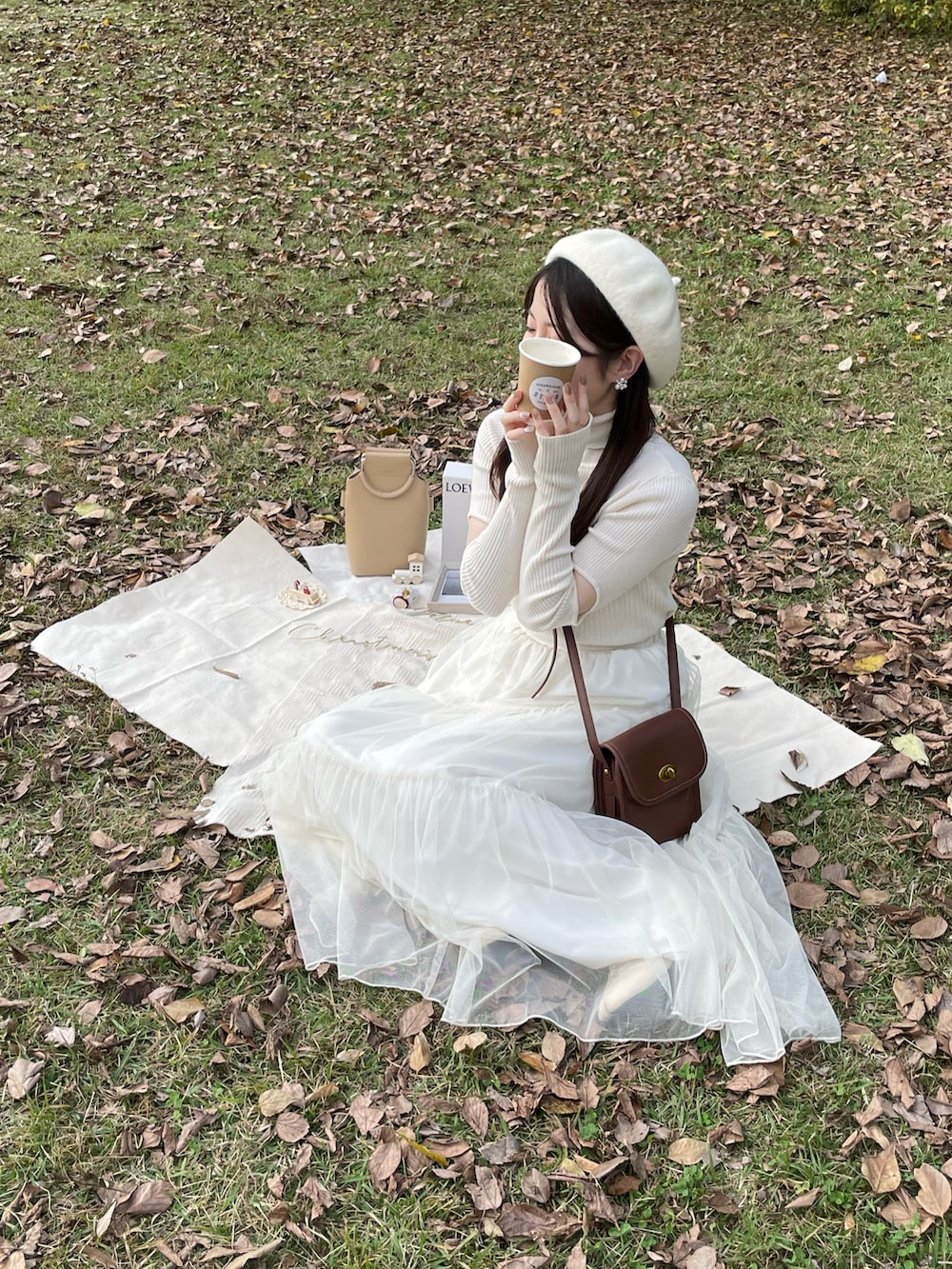 ホワイト系のニット/セーター、ホワイト系のカーディガン/ボレロ、ホワイト系のスカートを着用したレディースの秋コーディネートの2枚目の写真