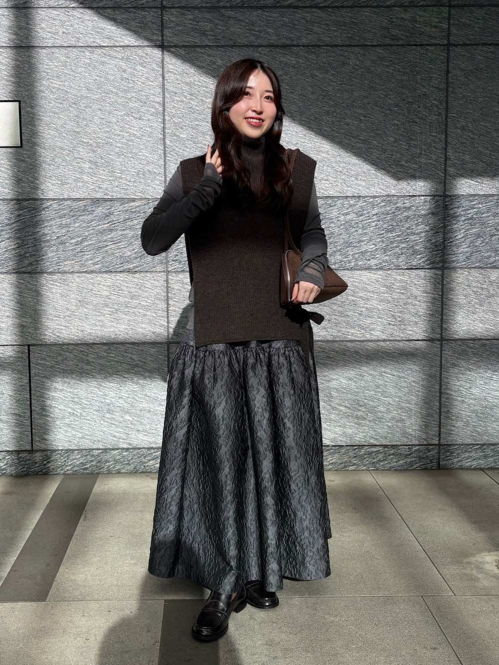 ブラウン系のニット/セーター、ブラウン系のビジネスバッグ、グレー系のTシャツ/カットソーを着用したレディースの冬コーディネートの2枚目の写真