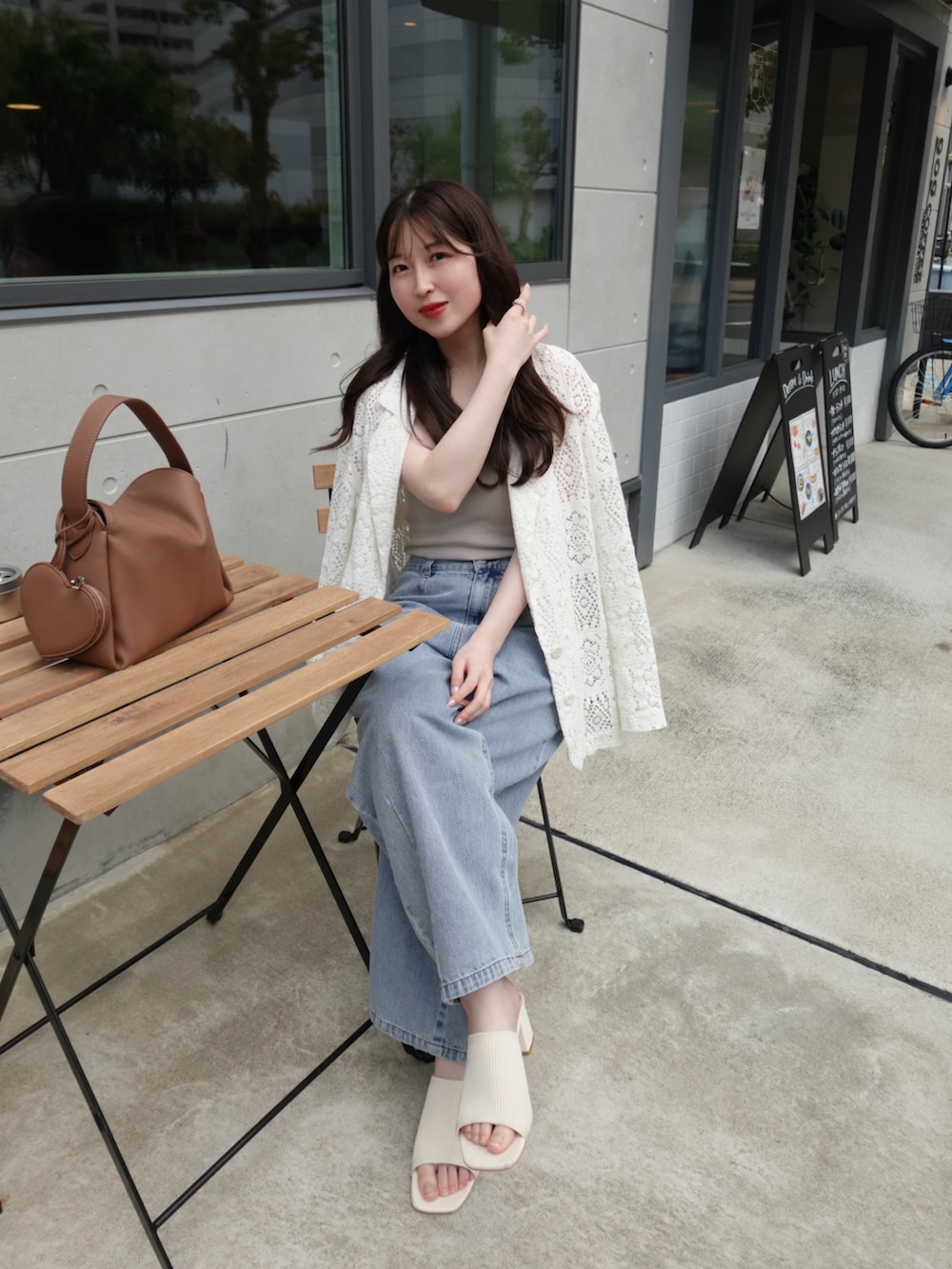 ベージュ系のキャミソール、ブルー系のデニムパンツ、ベージュ系のテーラードジャケットを着用したレディースの春コーディネートの2枚目の写真