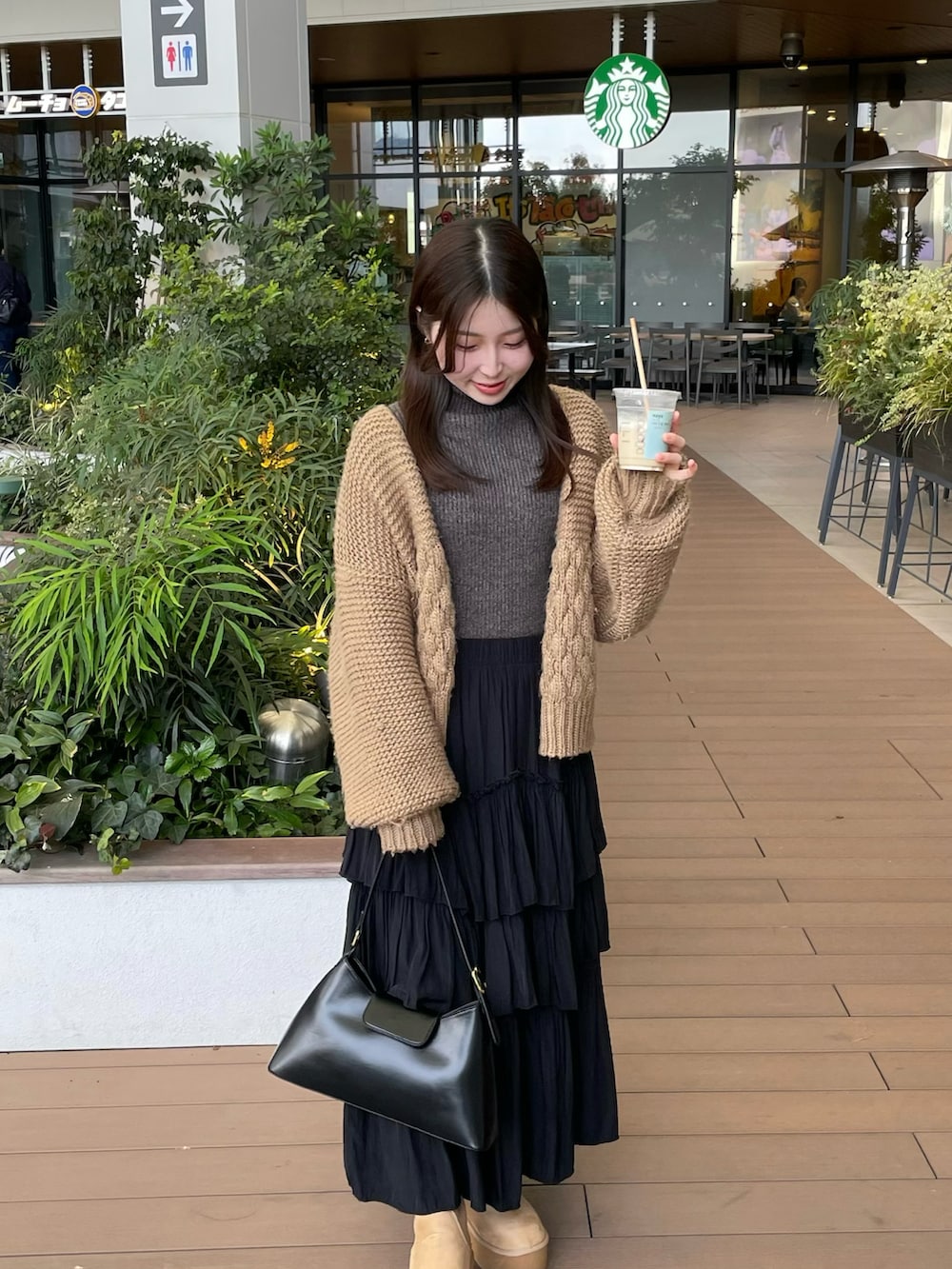 グレー系のニット/セーター、ベージュ系のカーディガン/ボレロ、ブラック系のスカートを着用したレディースの冬コーディネートの2枚目の写真