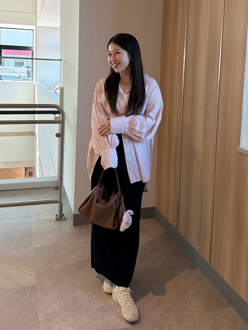 ホワイト系のスニーカー、ブラック系のスカート、イエロー系のハンドバッグを着用したレディースの春コーディネートの2枚目の写真