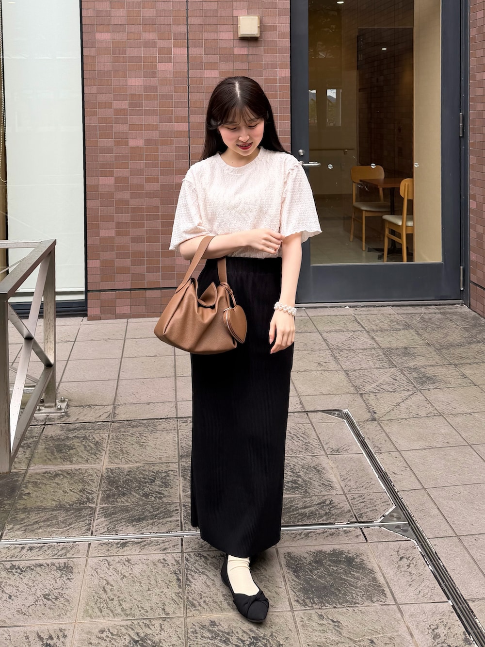 ブラック系のスカート、ホワイト系のTシャツ/カットソー、イエロー系のハンドバッグを着用したレディースの春コーディネートの4枚目の写真