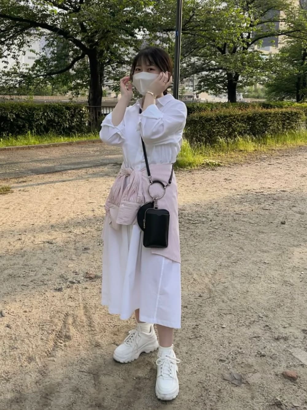 ホワイト系のシャツワンピース、ピンク系のシャツ/ブラウス、ホワイト系のスニーカーを着用したレディースの春コーディネートの2枚目の写真