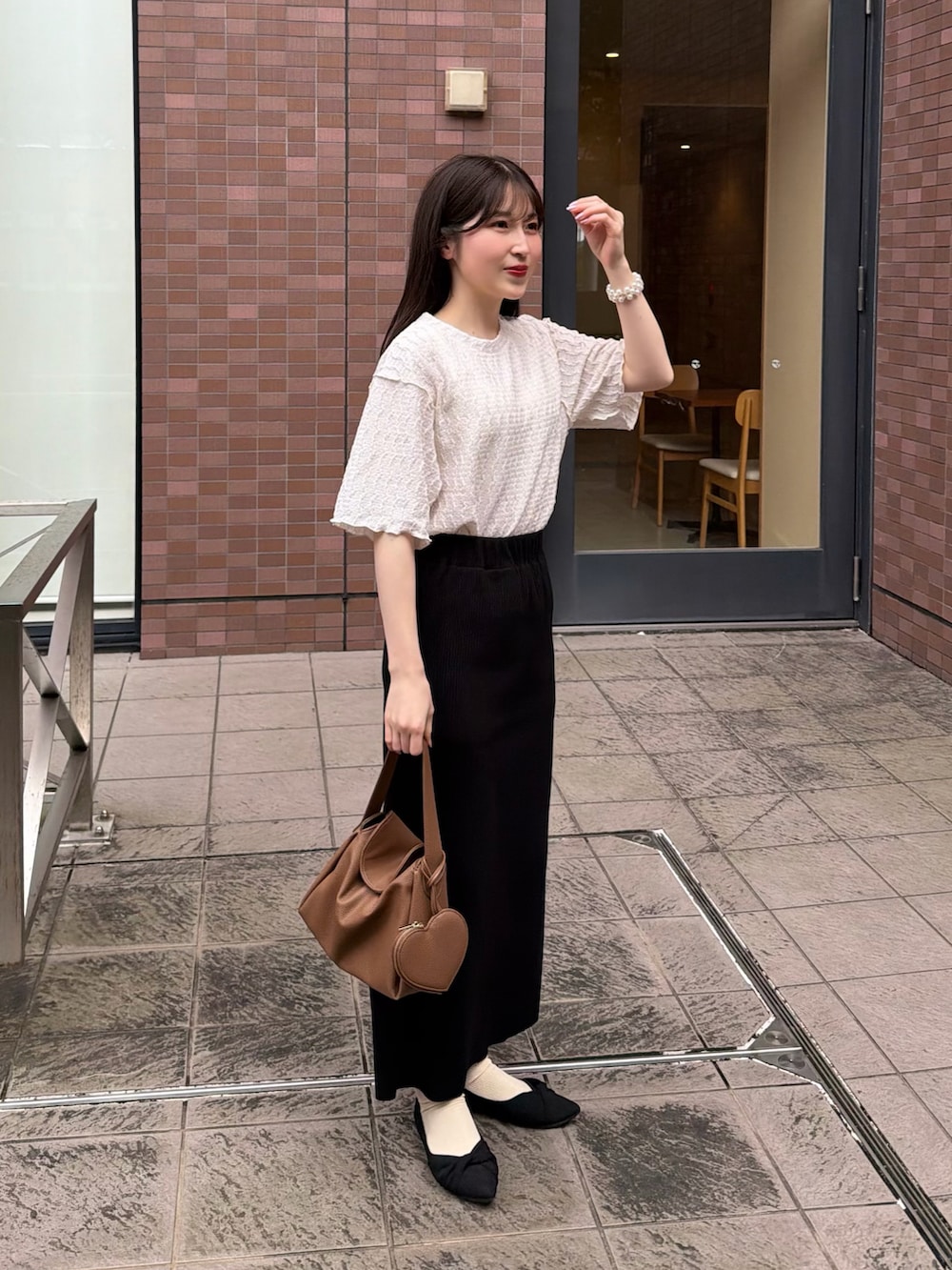 ブラック系のスカート、ホワイト系のTシャツ/カットソー、イエロー系のハンドバッグを着用したレディースの春コーディネートの2枚目の写真