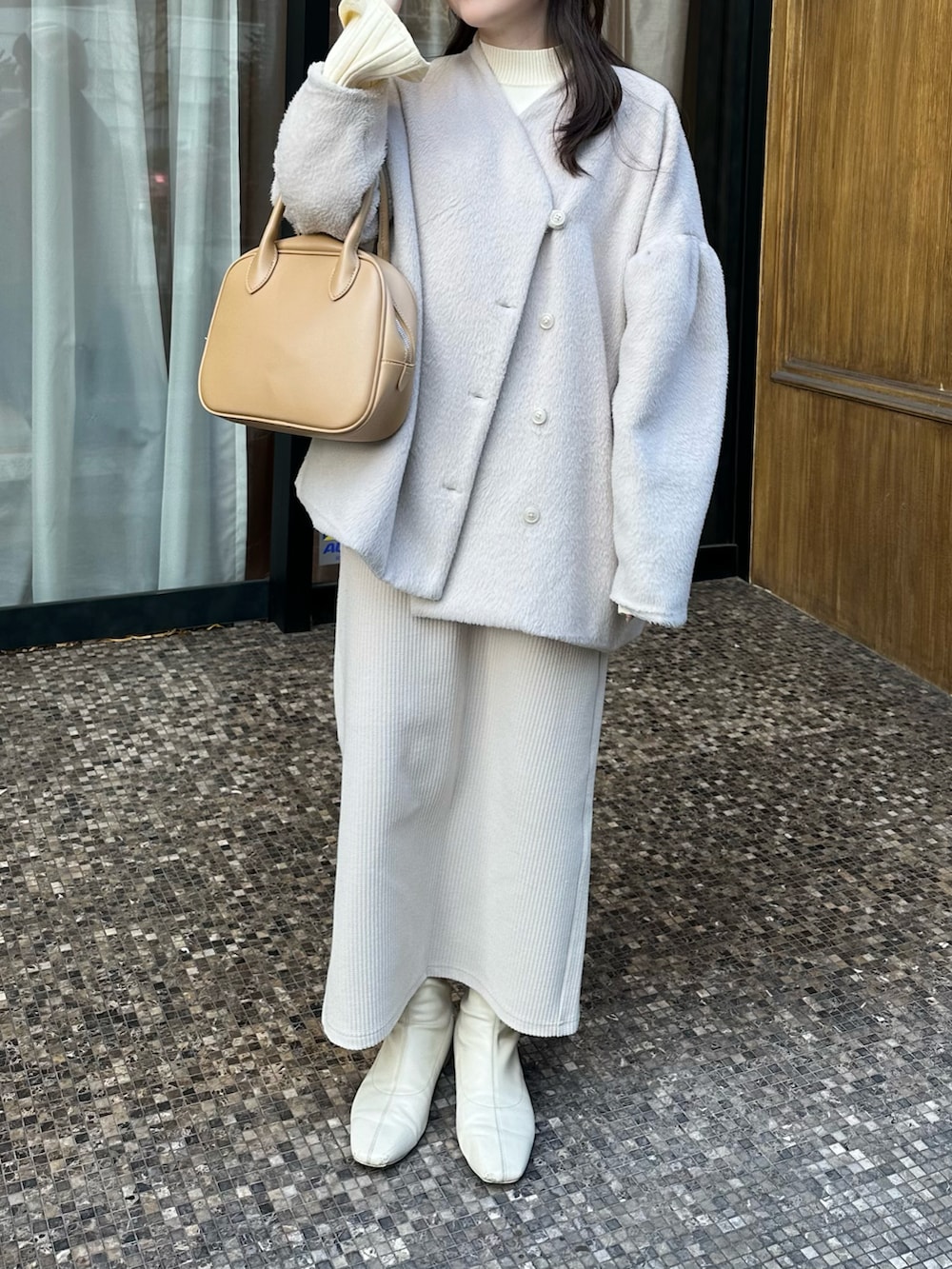ホワイト系のニット/セーター、ホワイト系のスカート、ホワイト系のその他アウターを着用したレディースの冬コーディネートの2枚目の写真
