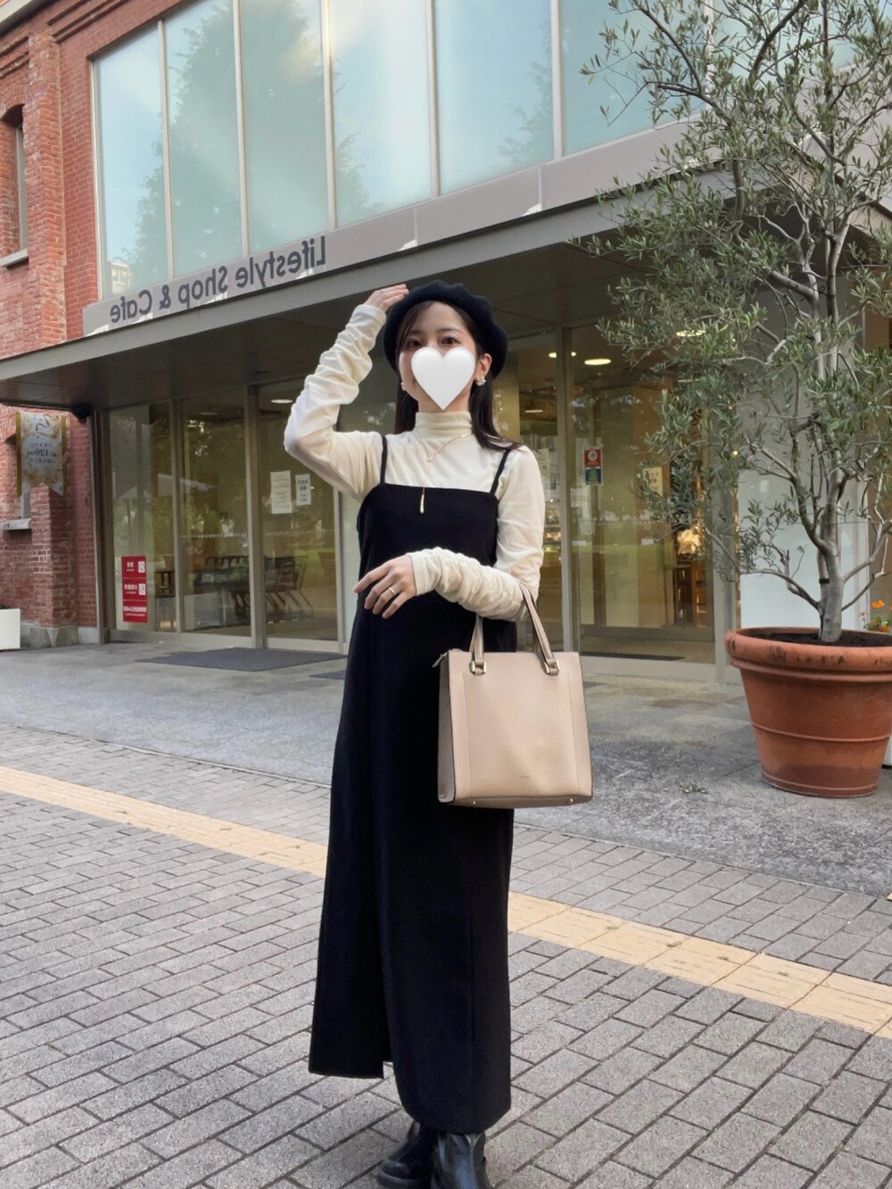 ホワイト系のTシャツ/カットソー、ブラック系のジャンパースカート、ブラック系のブーツを着用したレディースの秋コーディネートの2枚目の写真