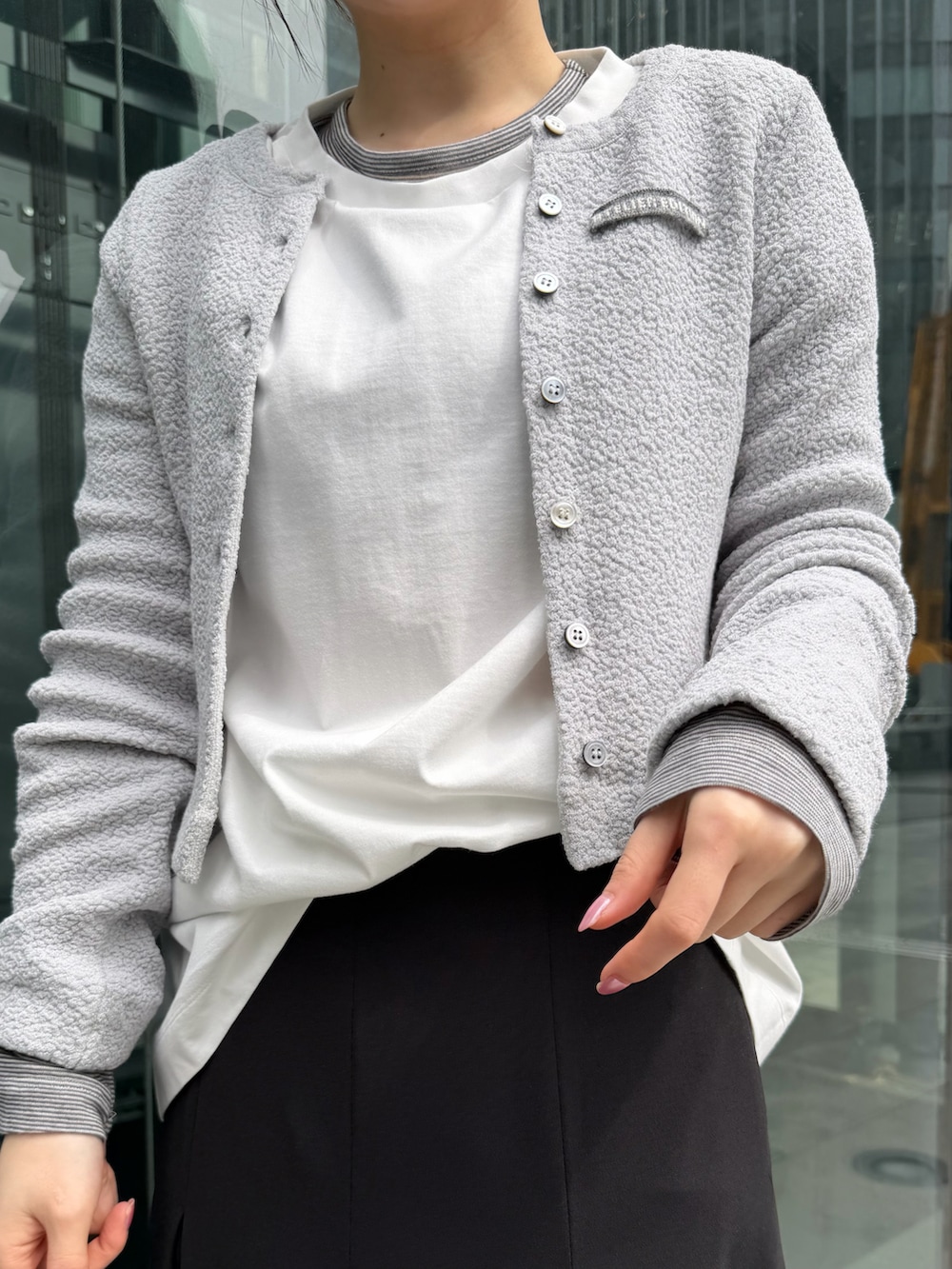 ホワイト系のTシャツ/カットソー、ブラック系のスカート、グレー系のカーディガン/ボレロを着用したレディースの春コーディネートの4枚目の写真