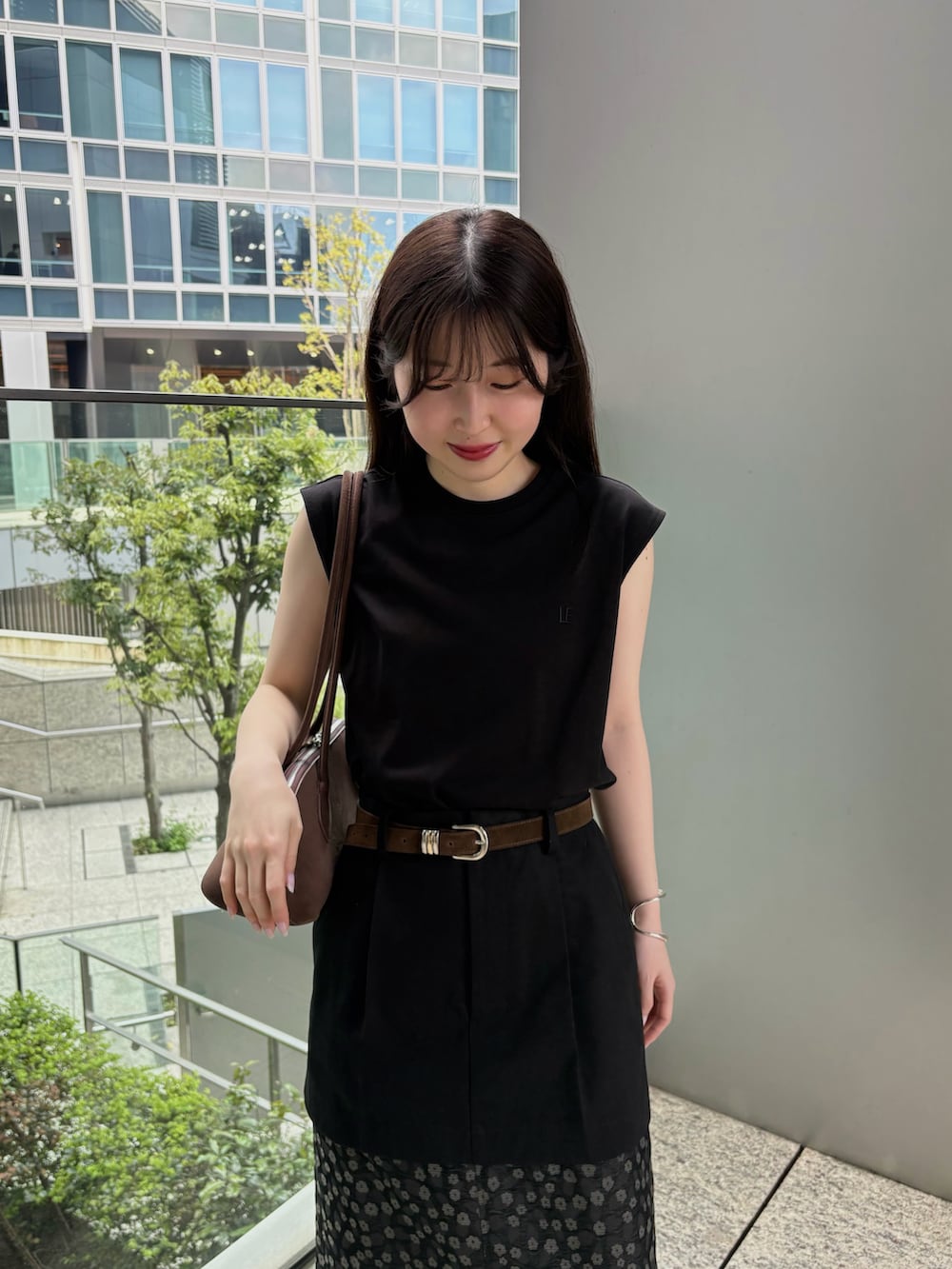 ブラウン系のビジネスバッグ、ブラック系のTシャツ/カットソー、ブラック系のスカートを着用したレディースの春コーディネートの3枚目の写真