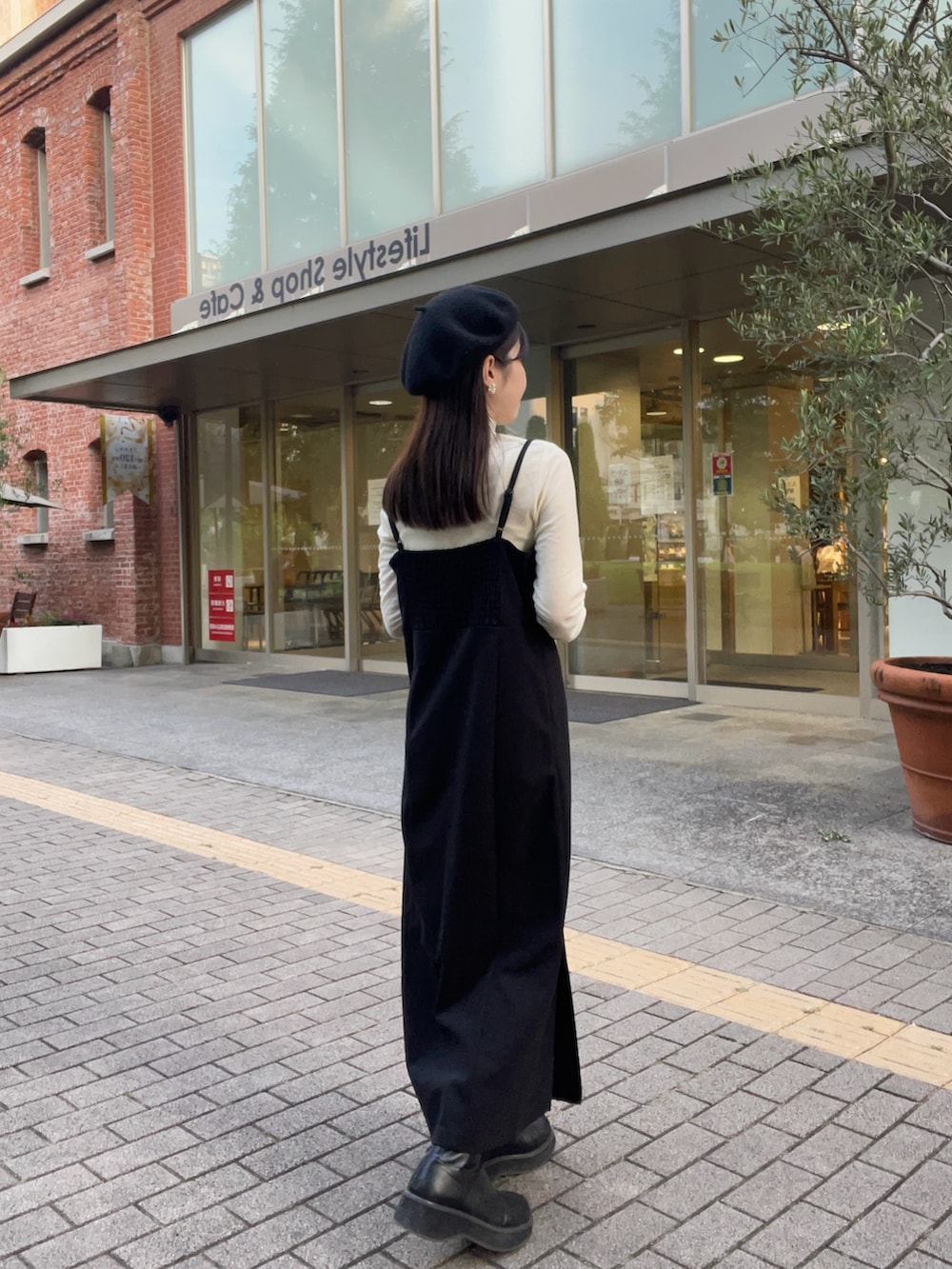 ホワイト系のTシャツ/カットソー、ブラック系のジャンパースカート、ブラック系のブーツを着用したレディースの秋コーディネートの3枚目の写真