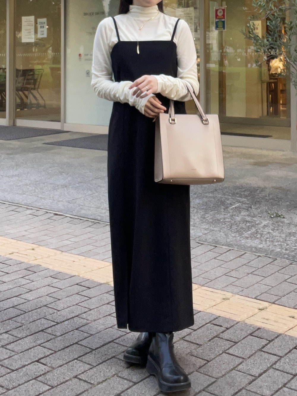 ホワイト系のTシャツ/カットソー、ブラック系のジャンパースカート、ブラック系のブーツを着用したレディースの秋コーディネートの4枚目の写真