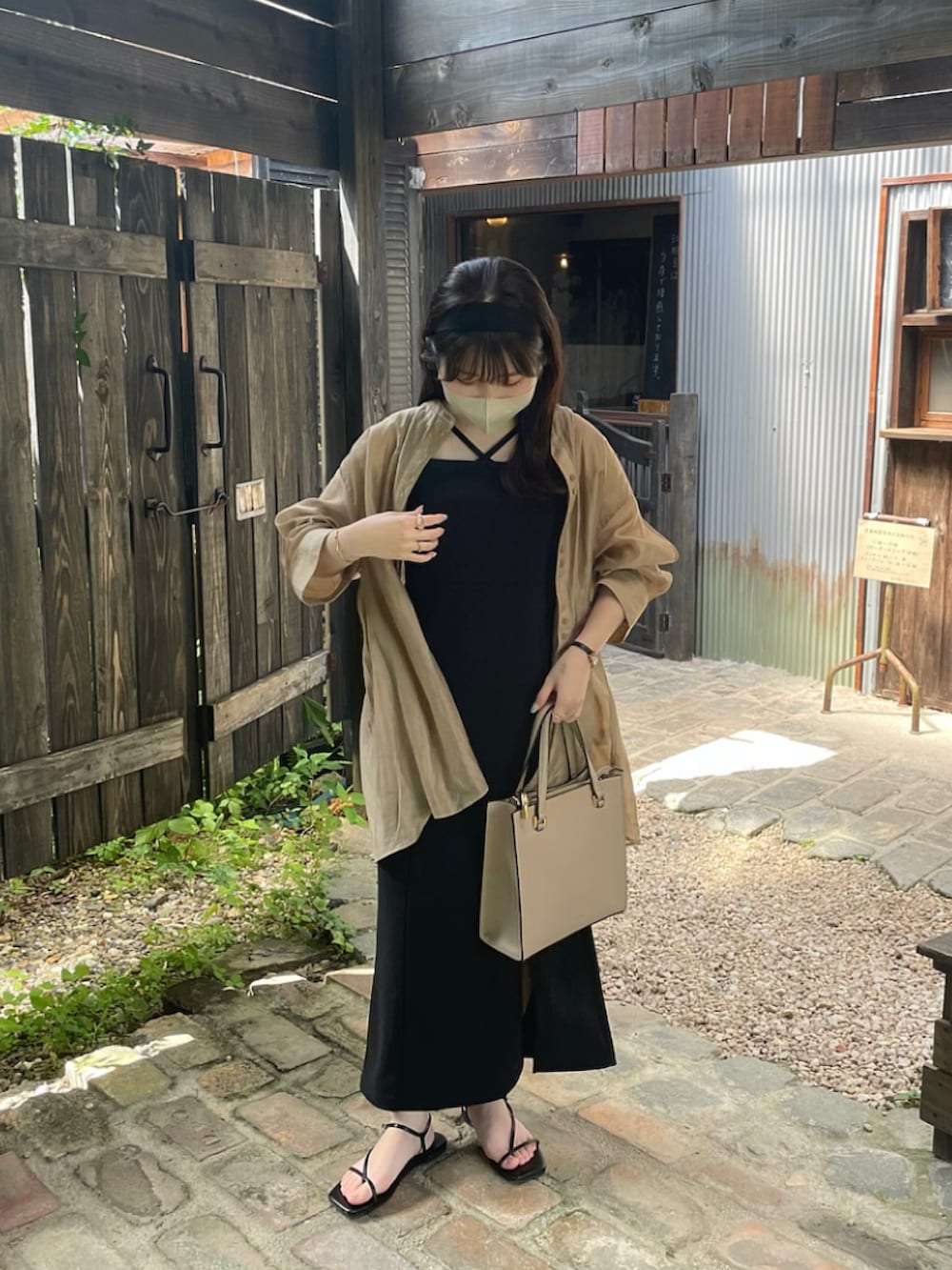 ブラック系のジャンパースカート、ベージュ系のシャツ/ブラウス、ブラック系のサンダルを着用したレディースの夏コーディネートの5枚目の写真