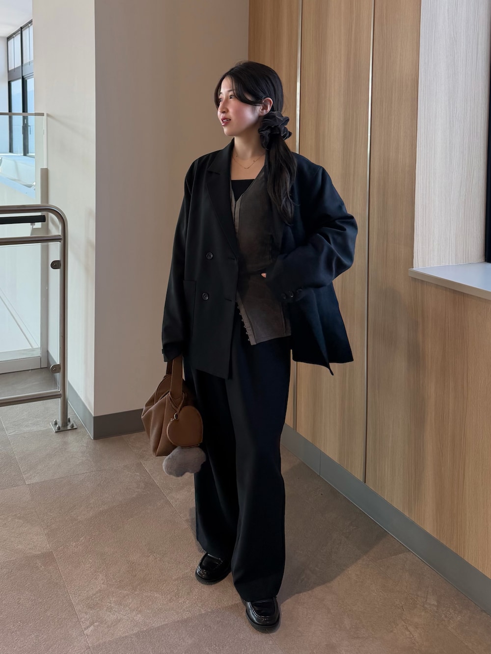 ブラック系のテーラードジャケット、グレー系のTシャツ/カットソー、ブラック系のスラックスを着用したレディースの冬コーディネートの2枚目の写真