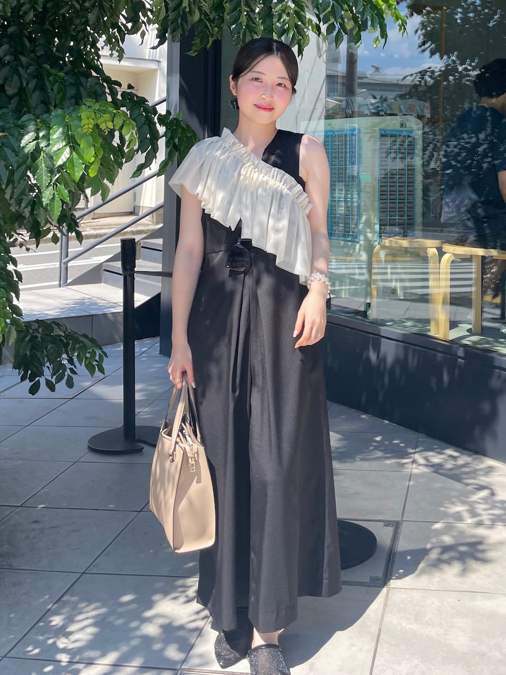 ブラック系のオールインワン・サロペット、ベージュ系のバッグ、ブラック系のシューズを着用したレディースの夏コーディネートの2枚目の写真