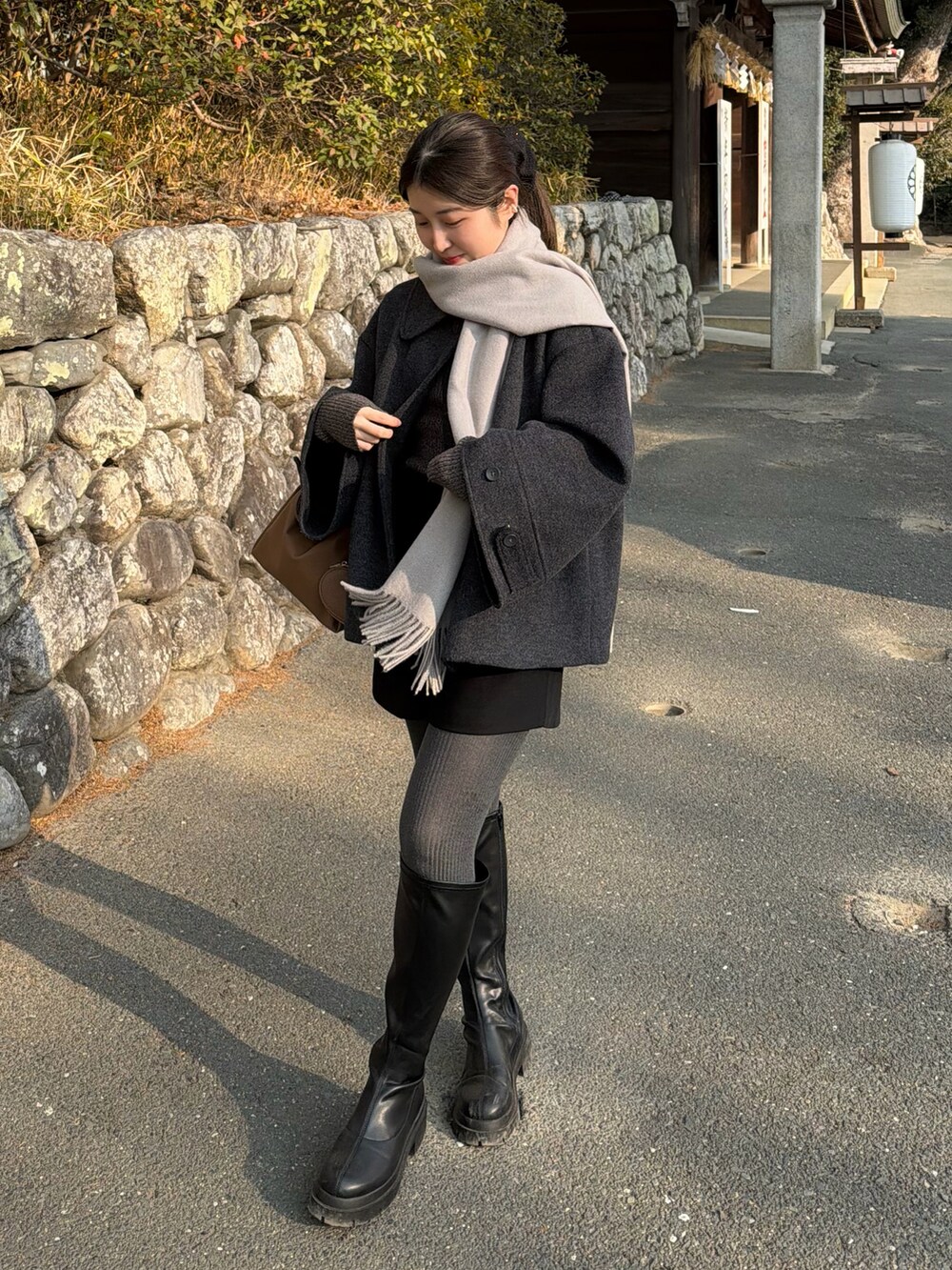 ブラック系のその他パンツ、グレー系のニット/セーター、イエロー系のハンドバッグを着用したレディースの冬コーディネートの2枚目の写真