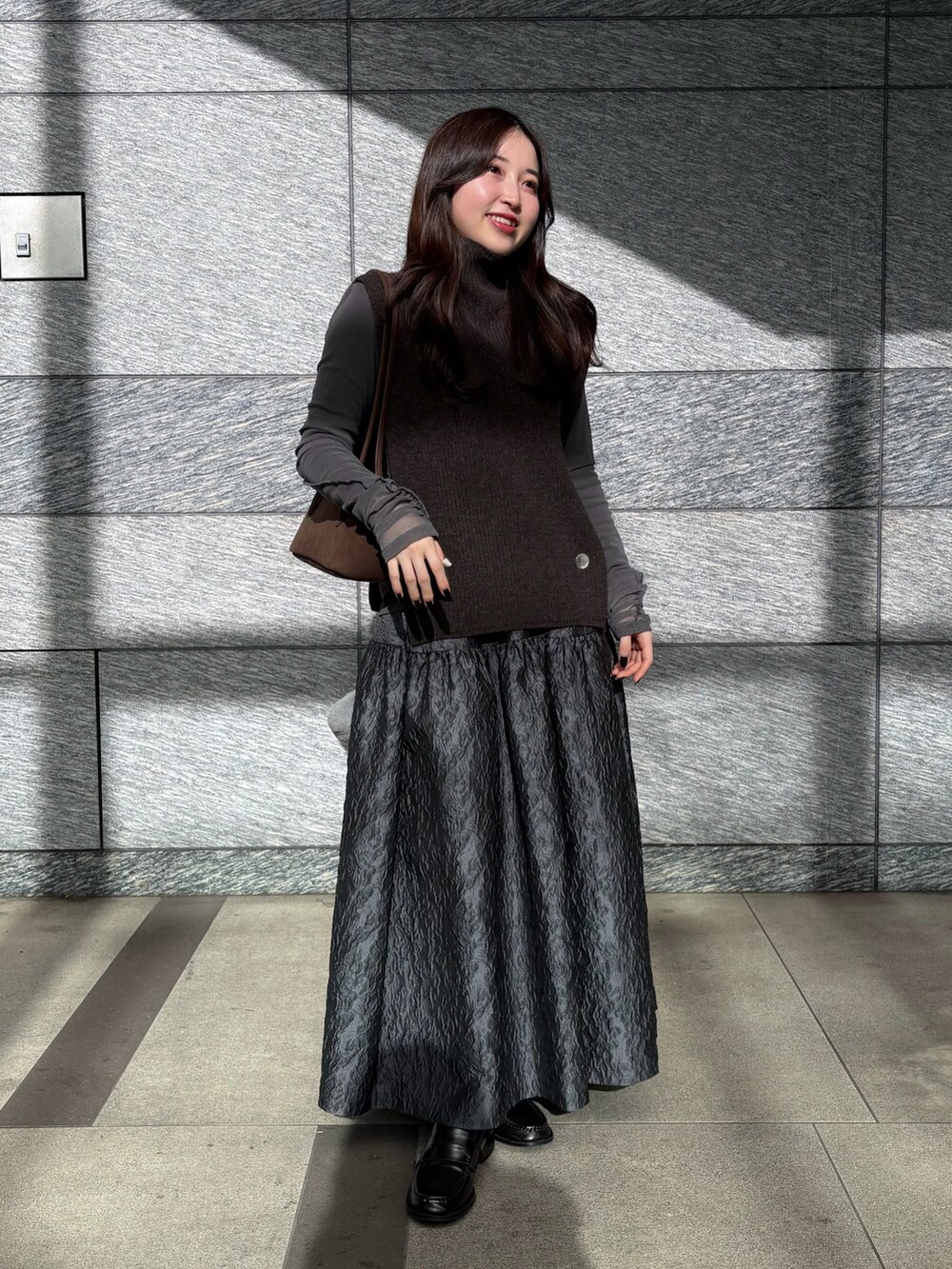 ブラウン系のニット/セーター、ブラウン系のビジネスバッグ、グレー系のTシャツ/カットソーを着用したレディースの冬コーディネートの5枚目の写真