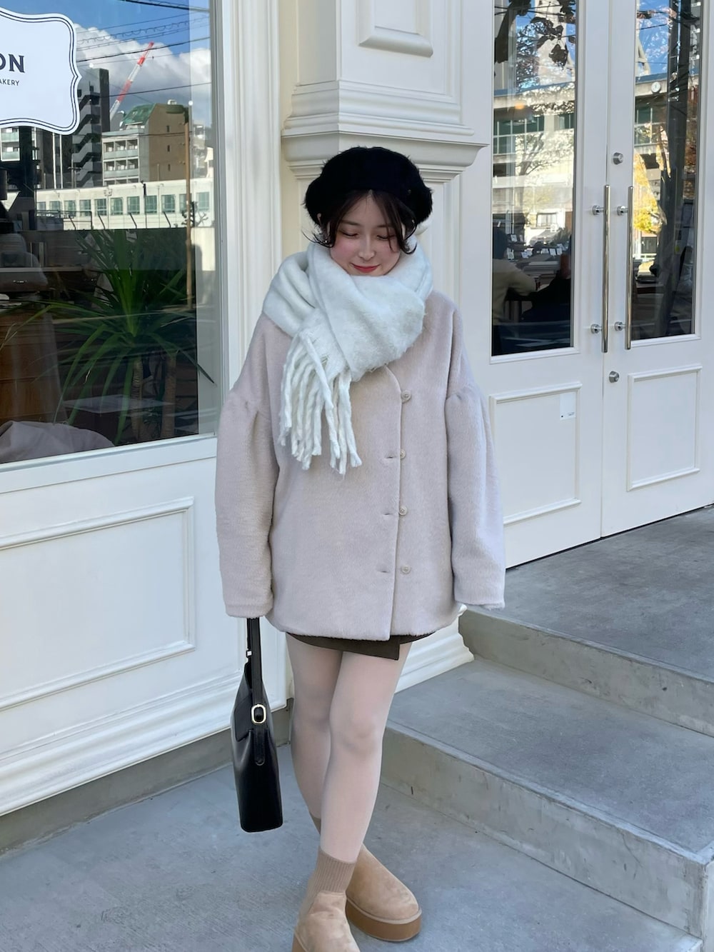 ホワイト系のその他アウター、ブラウン系のスカート、ベージュ系のブーツを着用したレディースの冬コーディネートの2枚目の写真