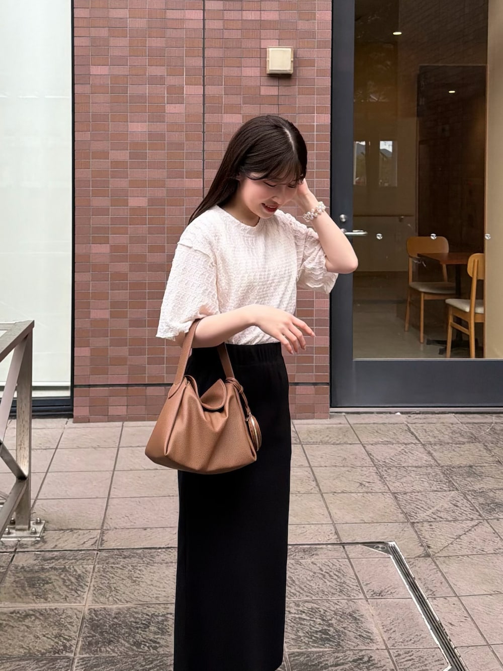 ブラック系のスカート、ホワイト系のTシャツ/カットソー、イエロー系のハンドバッグを着用したレディースの春コーディネートの5枚目の写真