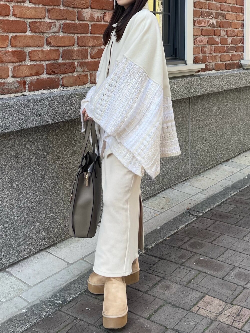 ホワイト系のポンチョ、ホワイト系のスカート、ベージュ系のブーツを着用したレディースの冬コーディネートの3枚目の写真