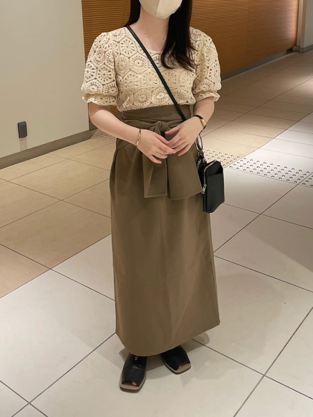 ベージュ系のシャツ/ブラウス、ベージュ系のスカート、ブラック系のサンダルを着用したレディースの夏コーディネートの2枚目の写真