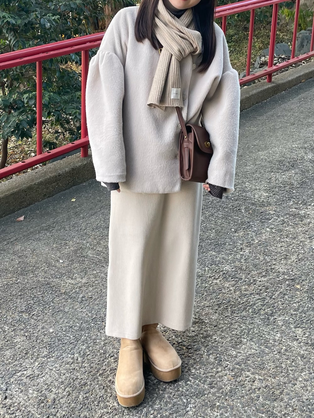 グレー系のニット/セーター、ホワイト系のスカート、ベージュ系のブーツを着用したレディースの冬コーディネートの3枚目の写真