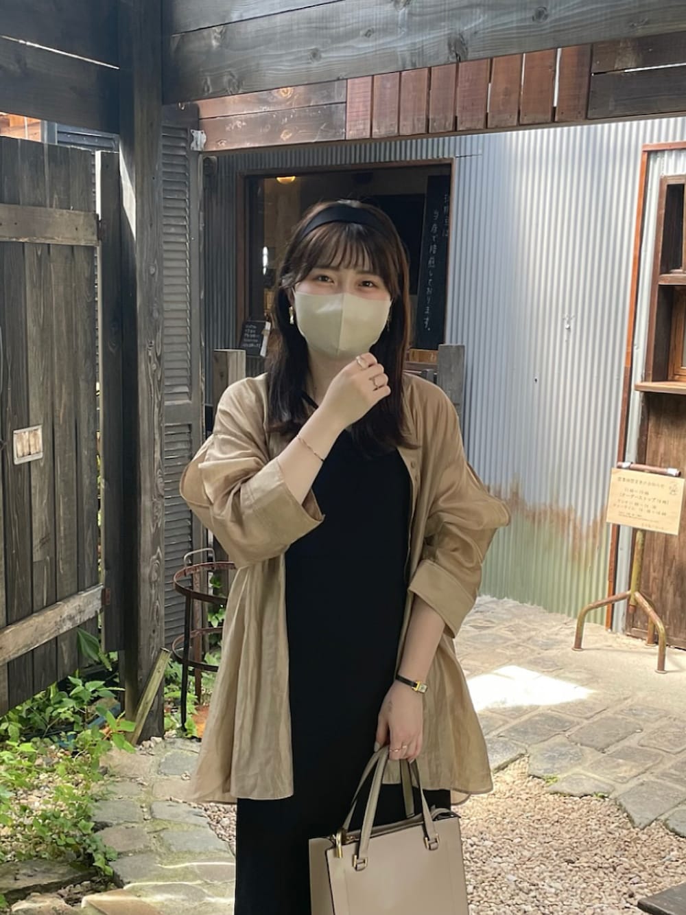 ブラック系のジャンパースカート、ベージュ系のシャツ/ブラウス、ブラック系のサンダルを着用したレディースの夏コーディネートの2枚目の写真