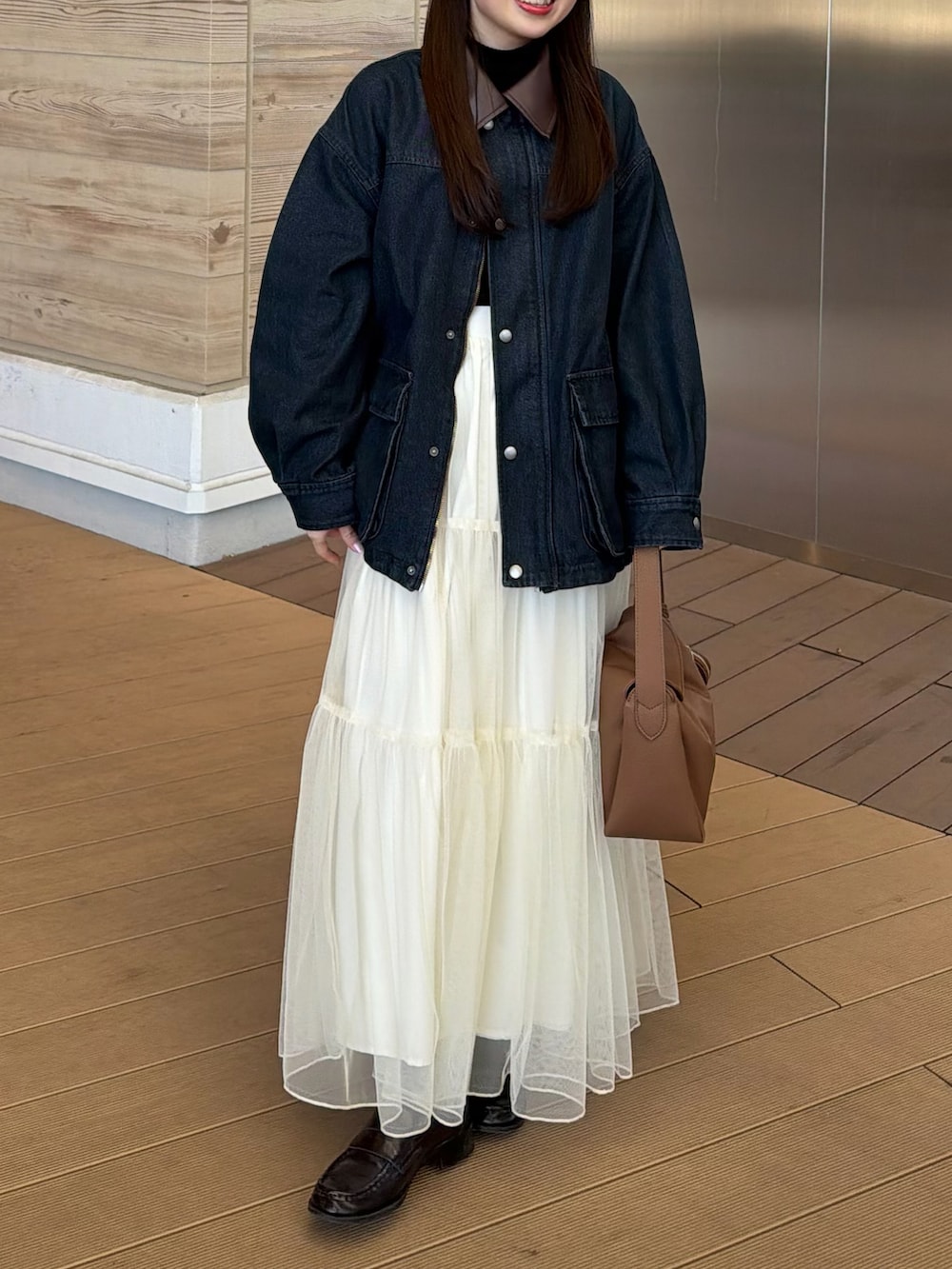 ブルー系のデニムジャケット、ブラック系のニット/セーター、ホワイト系のスカートを着用したレディースの冬コーディネートの4枚目の写真