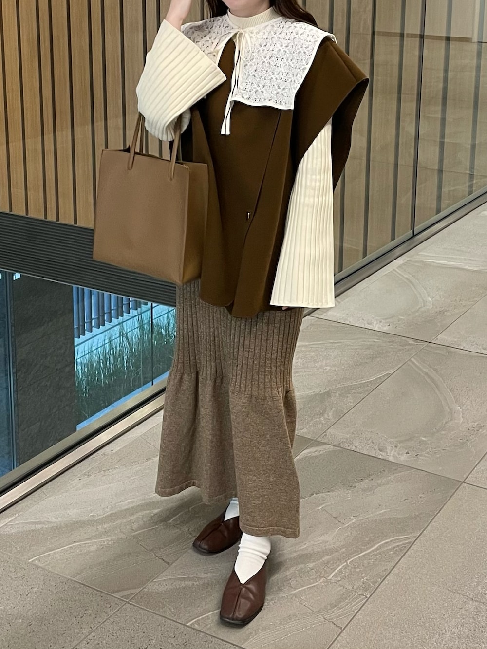 ホワイト系のニット/セーター、ブラウン系のベスト、ブラウン系のスカートを着用したレディースの冬コーディネートの2枚目の写真