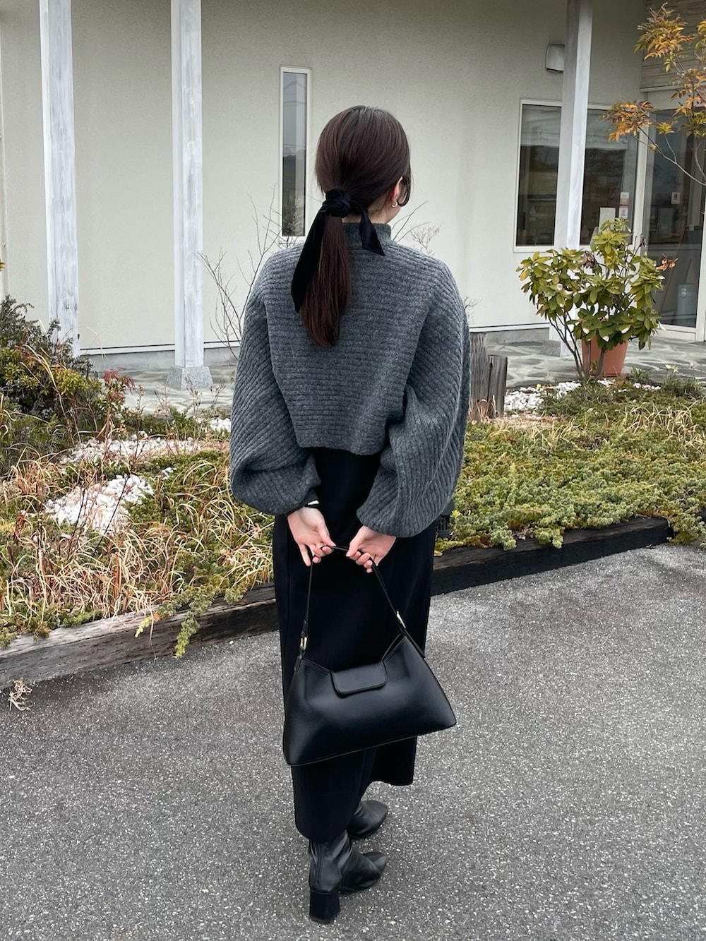 グレー系のワンピース、ブラック系のジャンパースカート、ブラック系のブーツを着用したレディースの冬コーディネートの2枚目の写真