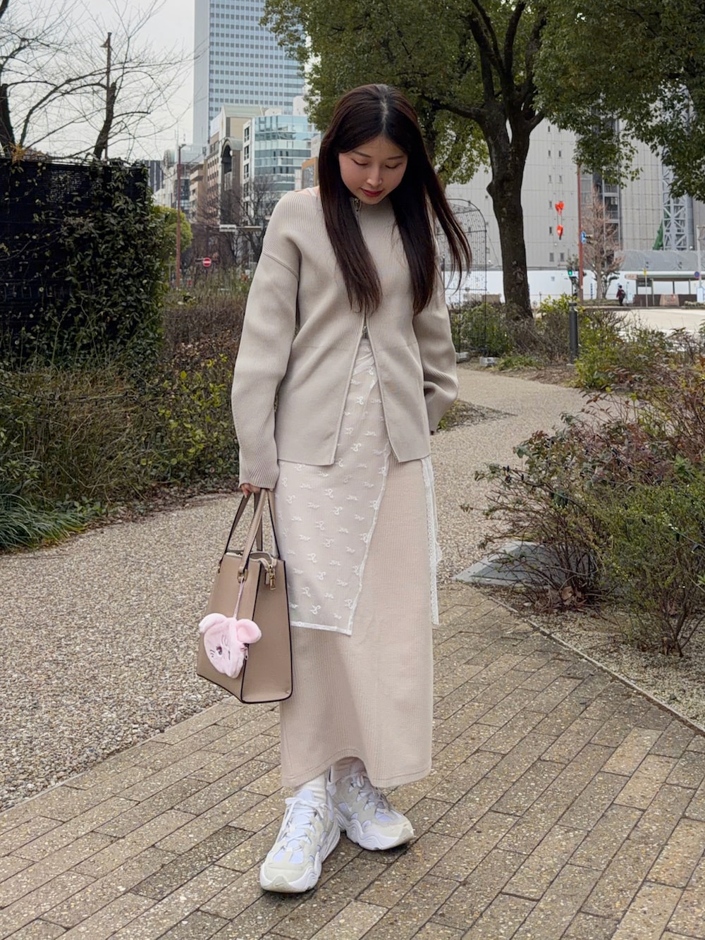 ベージュ系のカーディガン/ボレロ、ホワイト系のスニーカー、その他のスカートを着用したレディースの春コーディネートの4枚目の写真