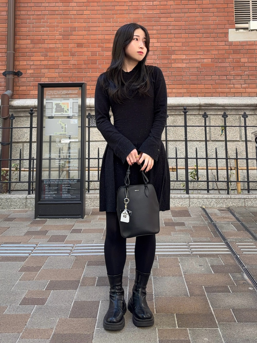 ブラック系のワンピース、ブラック系のブーツ、ブラック系のハンドバッグを着用したレディースの秋コーディネートの4枚目の写真