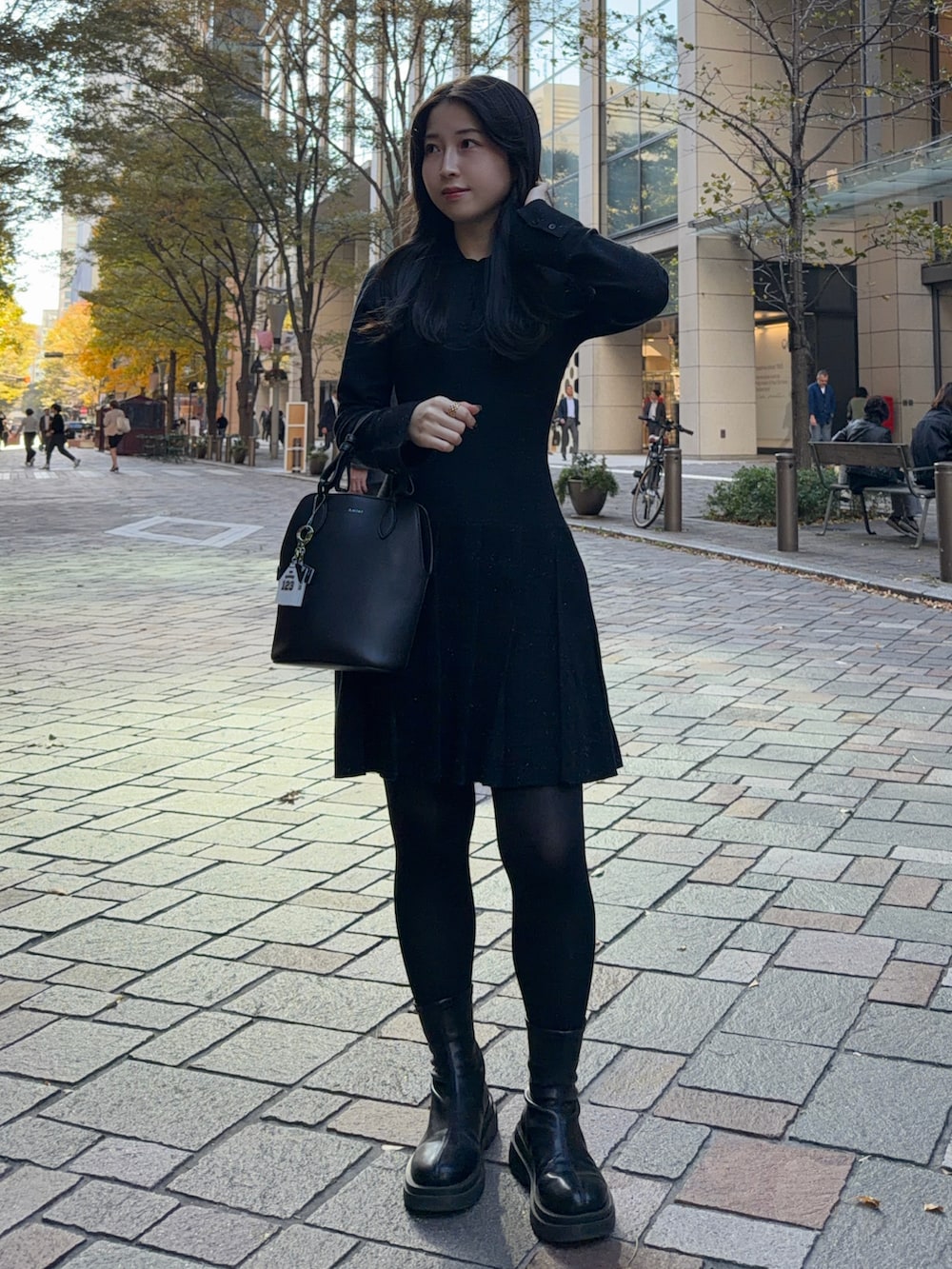 ブラック系のワンピース、ブラック系のブーツ、ブラック系のハンドバッグを着用したレディースの秋コーディネートの2枚目の写真