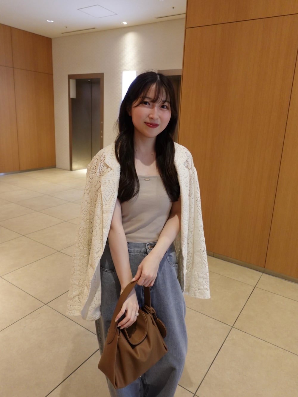 ベージュ系のキャミソール、ブルー系のデニムパンツ、ベージュ系のテーラードジャケットを着用したレディースの春コーディネートの3枚目の写真